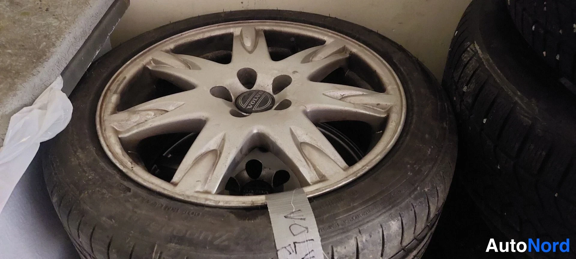 Muu: Hopea Volvo-alkuperäisvanne kesärenkaalla, renkaan kyljessä tapeilla merkintä 'VOLVO'.