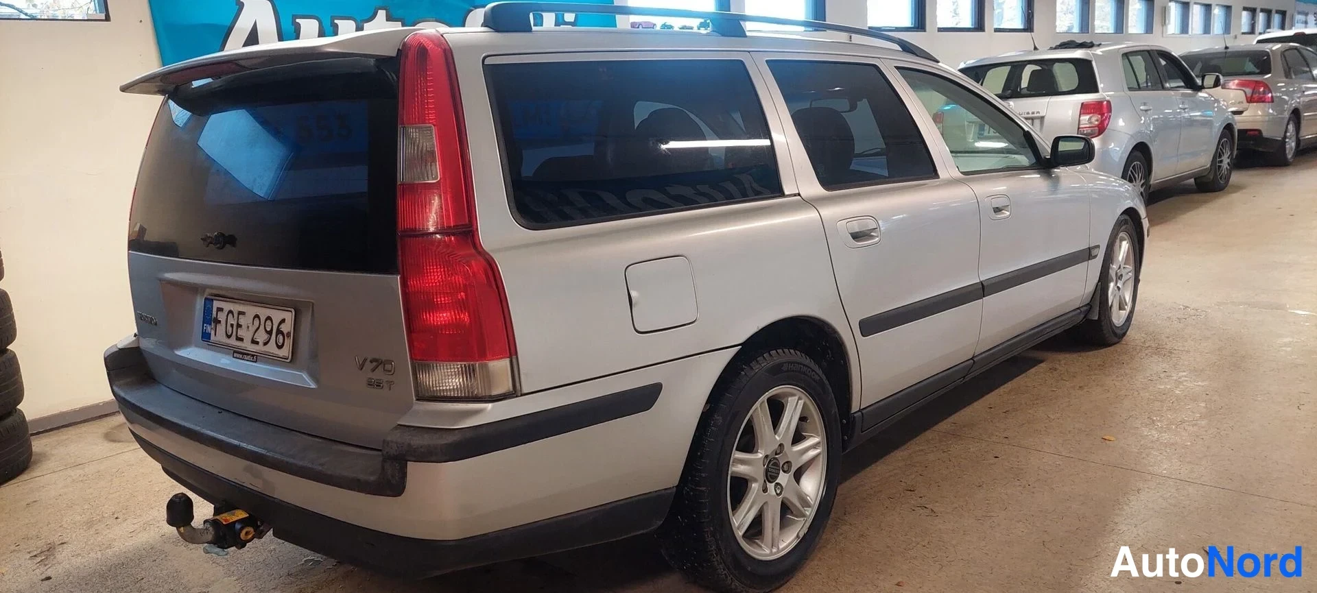 Takaviisto: Hopeisen Volvo V70 -farmaarin takakulma vasemmalta, rekisterikilpi, V70 2.5T -teksti takaoven alaosassa.