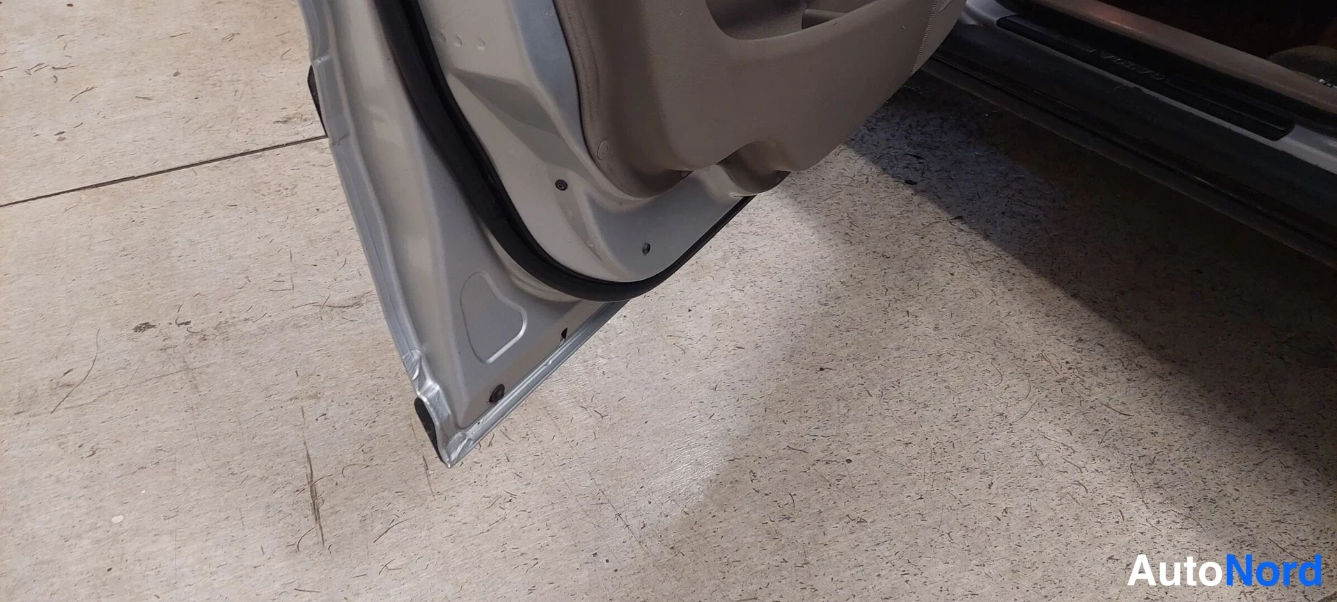 Muu: Avatun oven reuna ja ovikynnys lähikuvassa, autoa ei näy kokonaan.