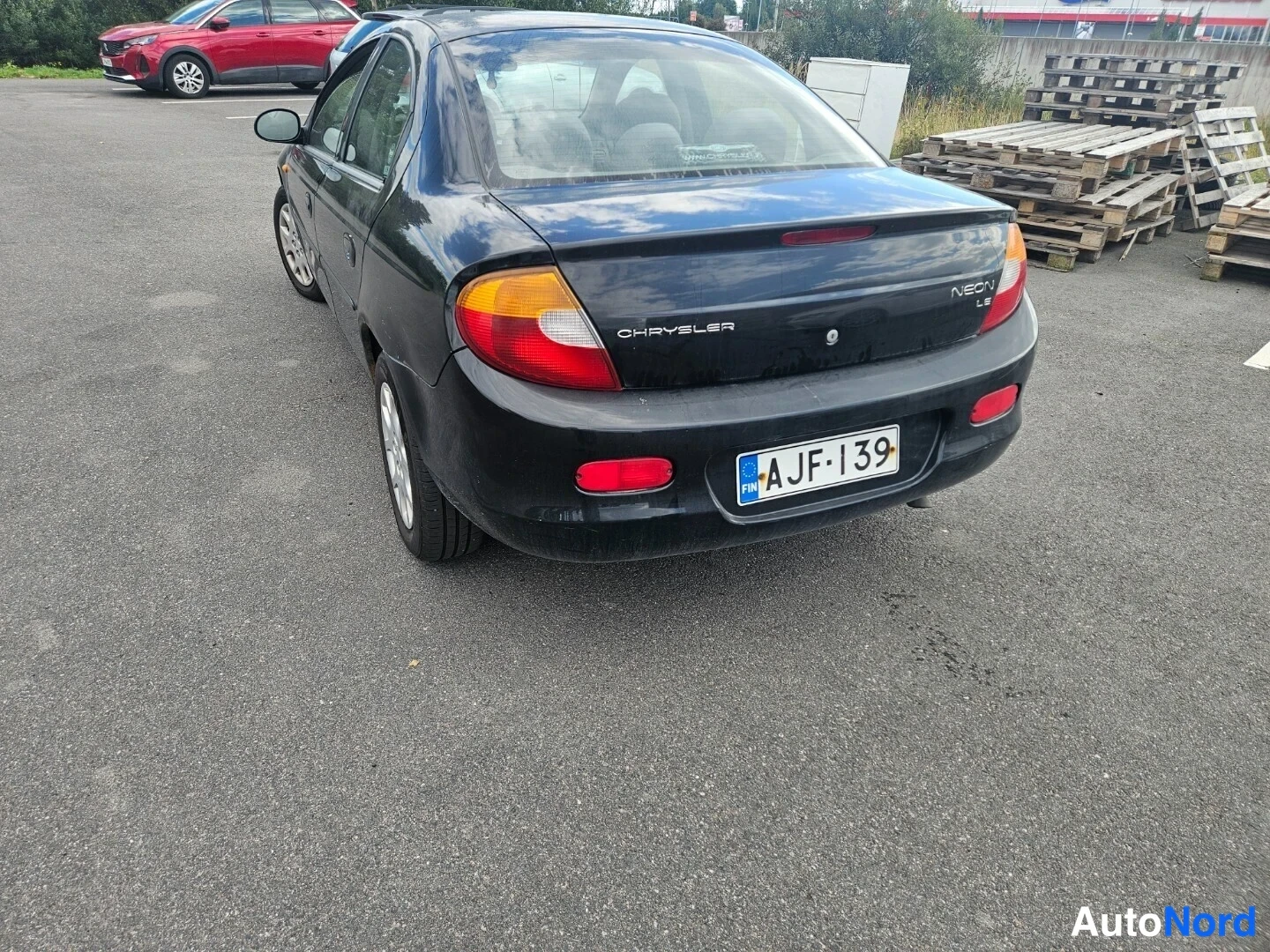 Takaviisto: Musta Chrysler Neon takakulmasta, peräkori ja CHRYSLER-merkintä näkyvät, rekisteritunnus.