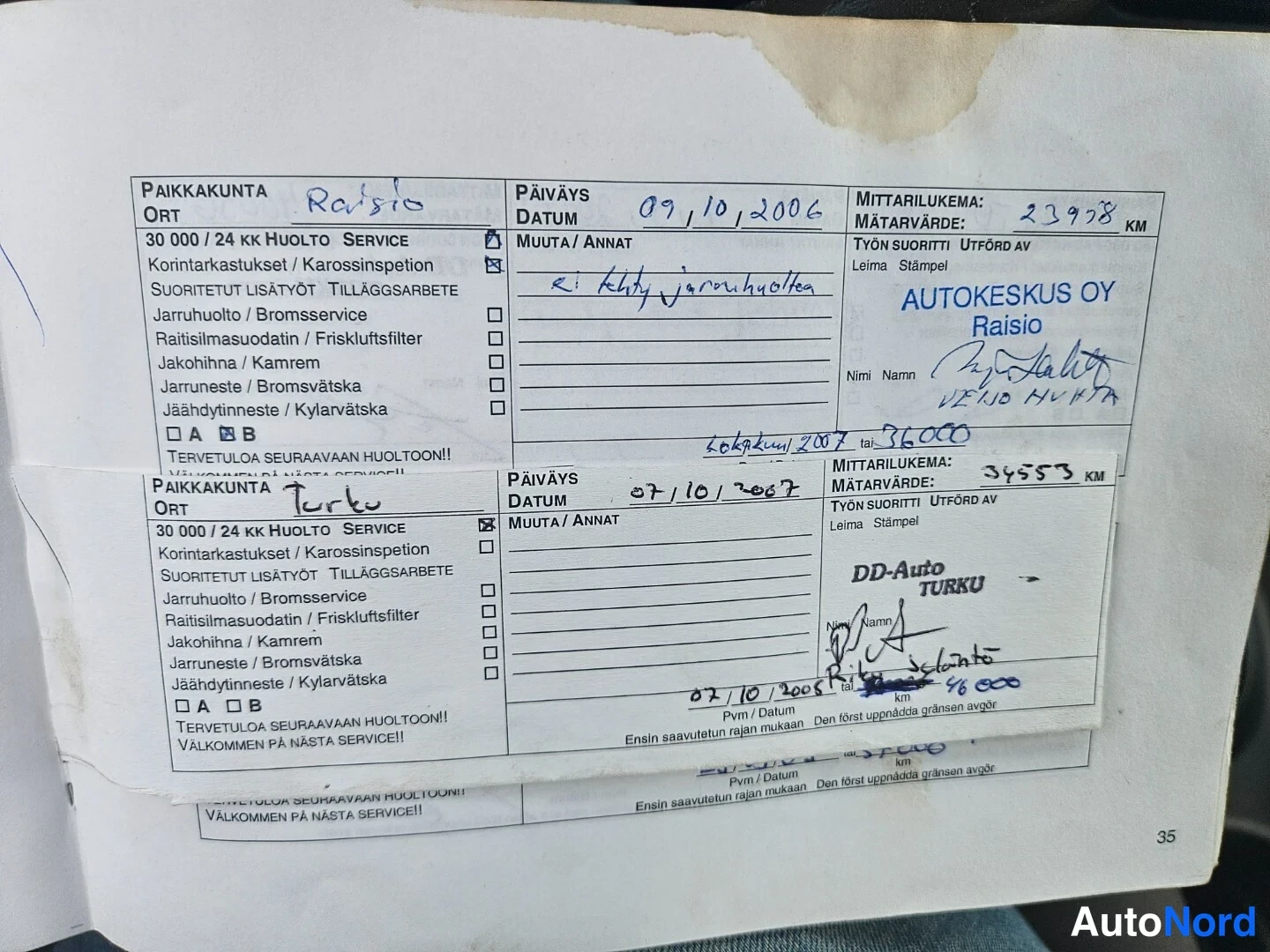 Asiakirja: Palvelutodistuksen sivu, jossa näkyvät useammat huoltomerinnät: päivämäärät 09/10/2006 (mittari 23978 km) ja 07/10/2007 (mittari 34553 km), sekä rivi vuodelta 0