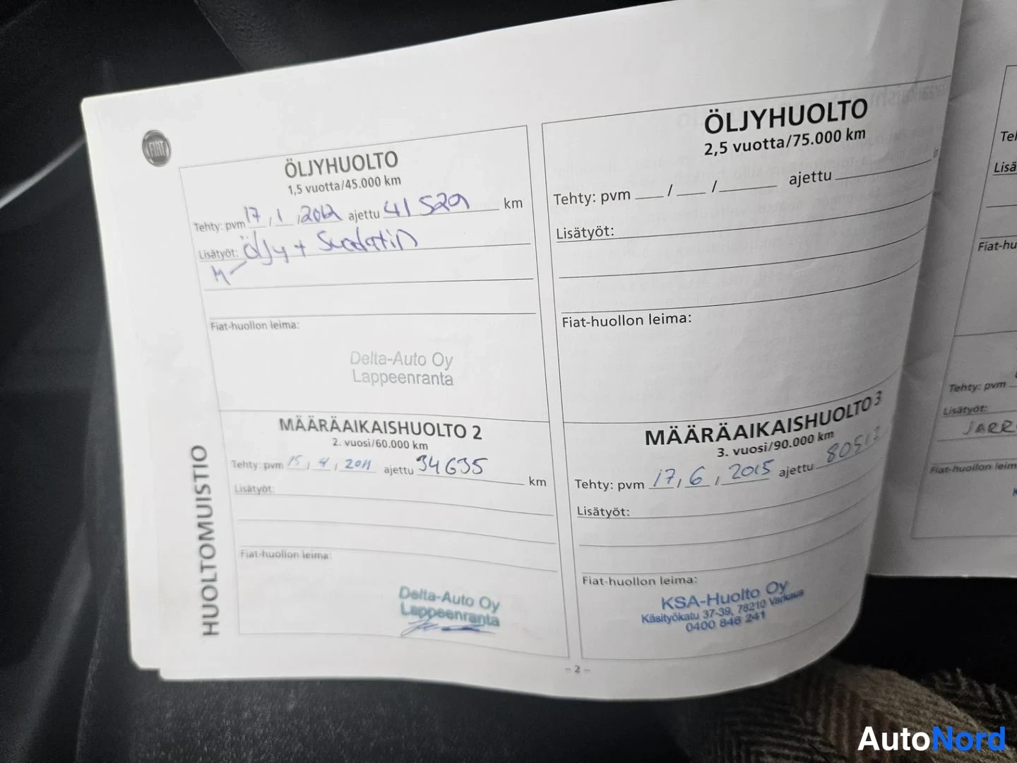 Yksityiskohta: Huoltomuistion avattu sivu, jossa öljyhuolto- ja määräaikaishuolto-merkinnät käsin täytettynä.