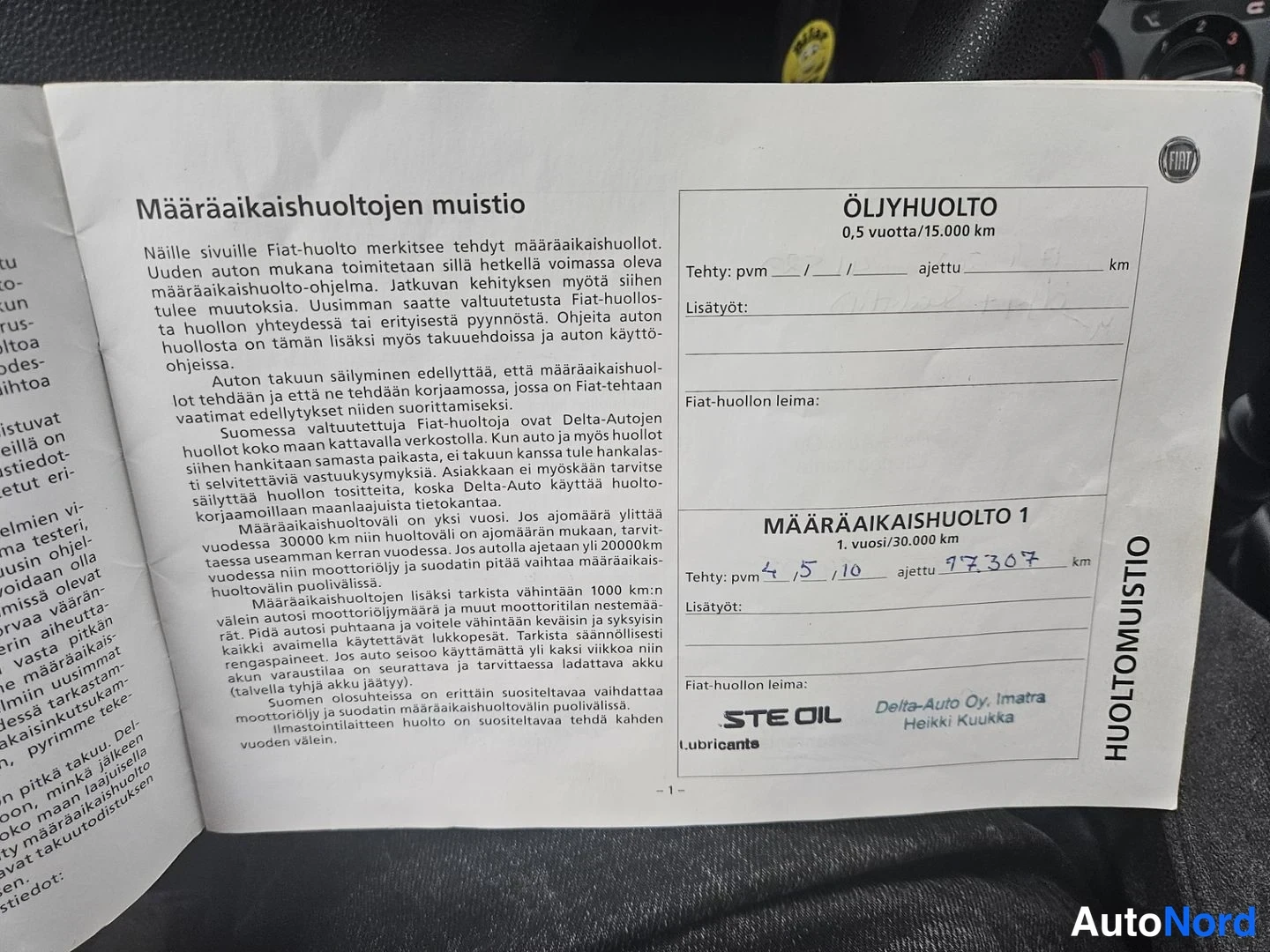 Yksityiskohta: Huoltomuistion tekstisivu ja ensimmäisen määräaikaishuollon merkintä Fiat-huollon leimalla.