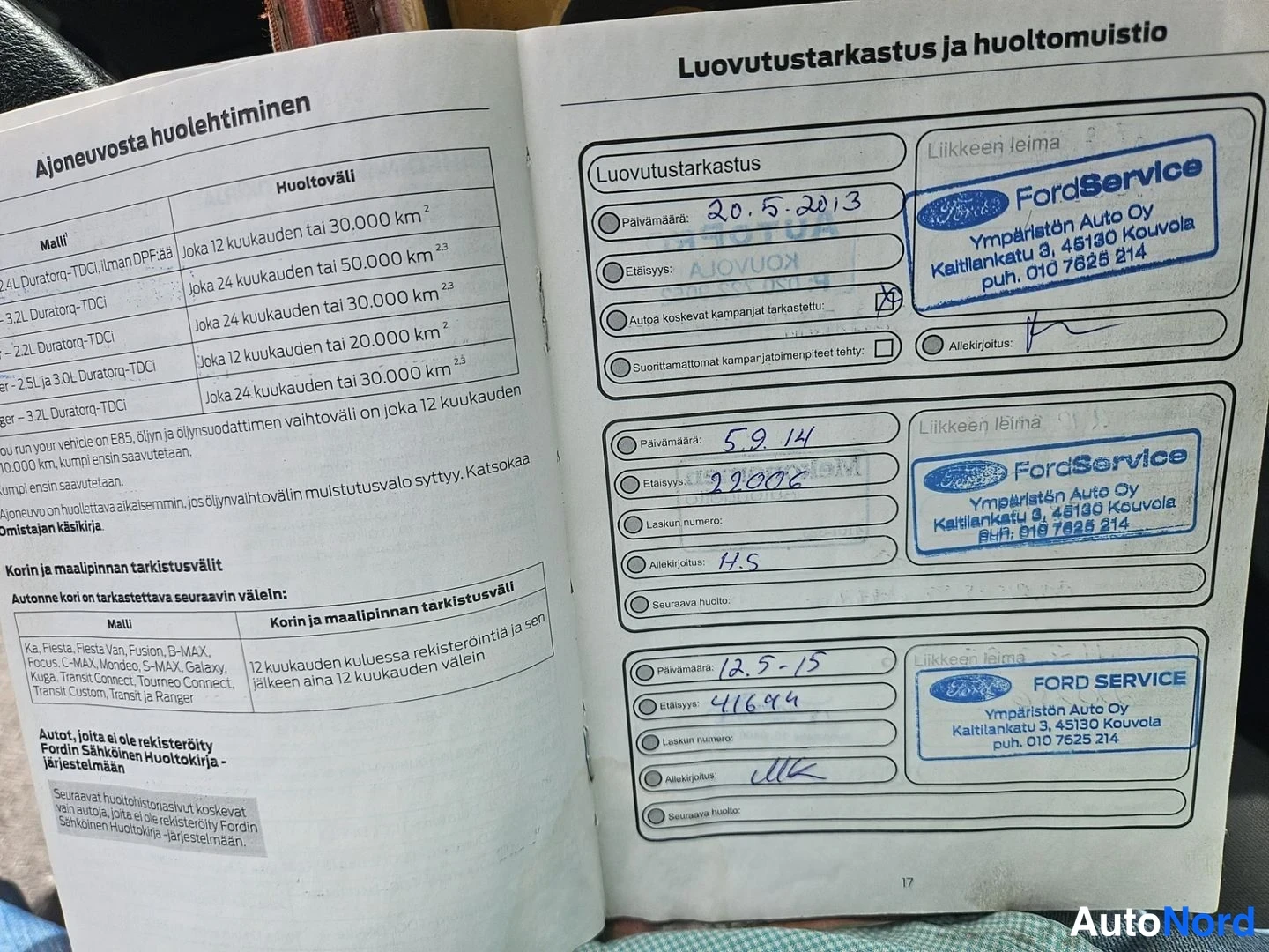 Yksityiskohta: Auki käännetty huoltokirja, jonka sivulla luovutustarkastusmerkinnät ja FordService-leimat.