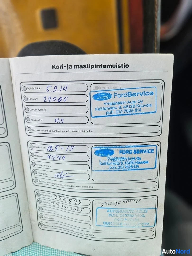Yksityiskohta: Huoltokirjan sivu 21, Kori- ja maalipintamuistio, kolme merkintää FordService-leimoilla (Ympäristön Auto Oy, Kouvola) ja yksi Autihuolto Julis -leima.