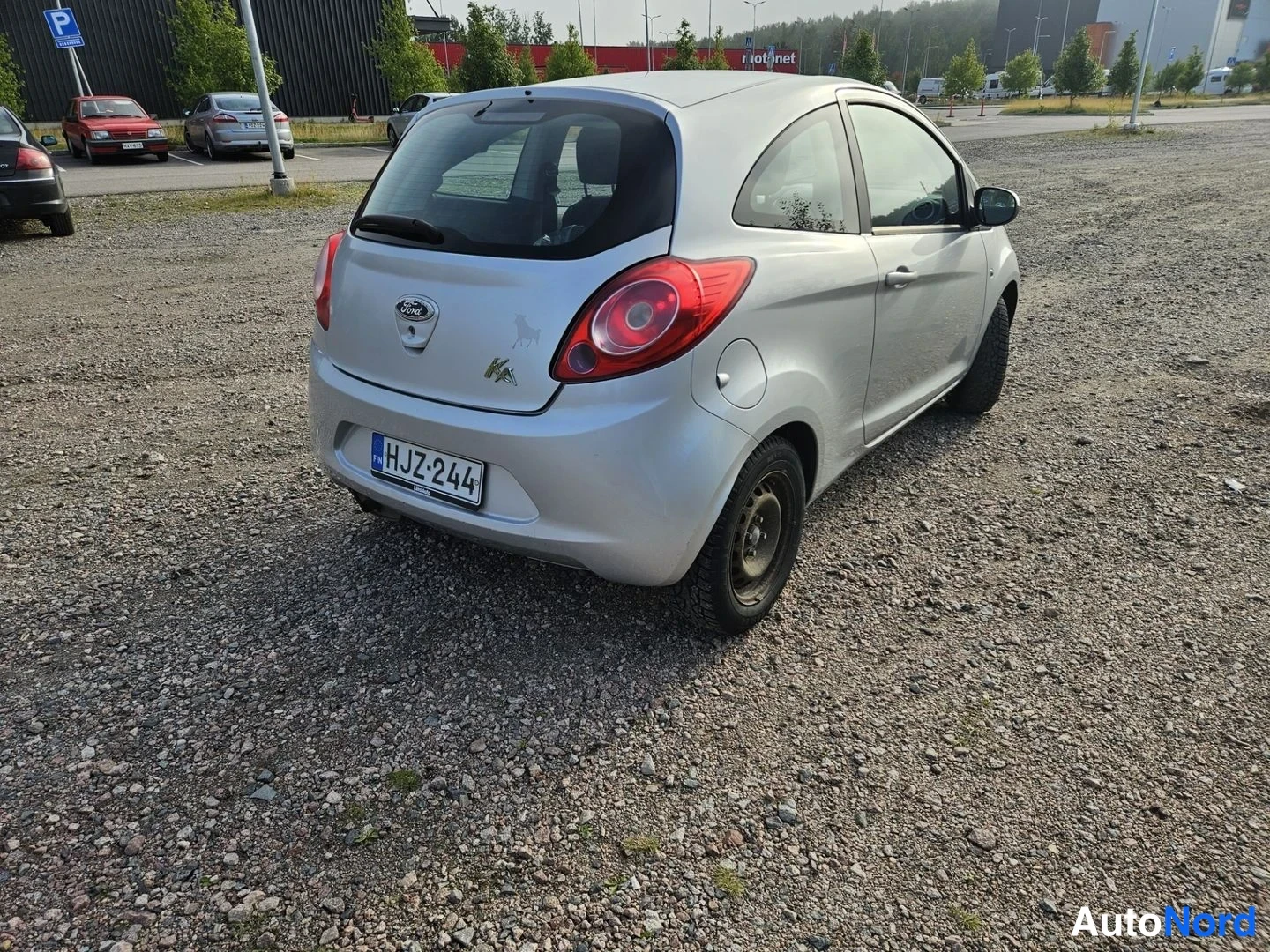 Takaviisto: Hopeanvärinen Ford Ka takaa ja oikealta päin kuvattuna sorapohjaisella parkkipaikalla, rekisteri näkyy takapuskurissa.