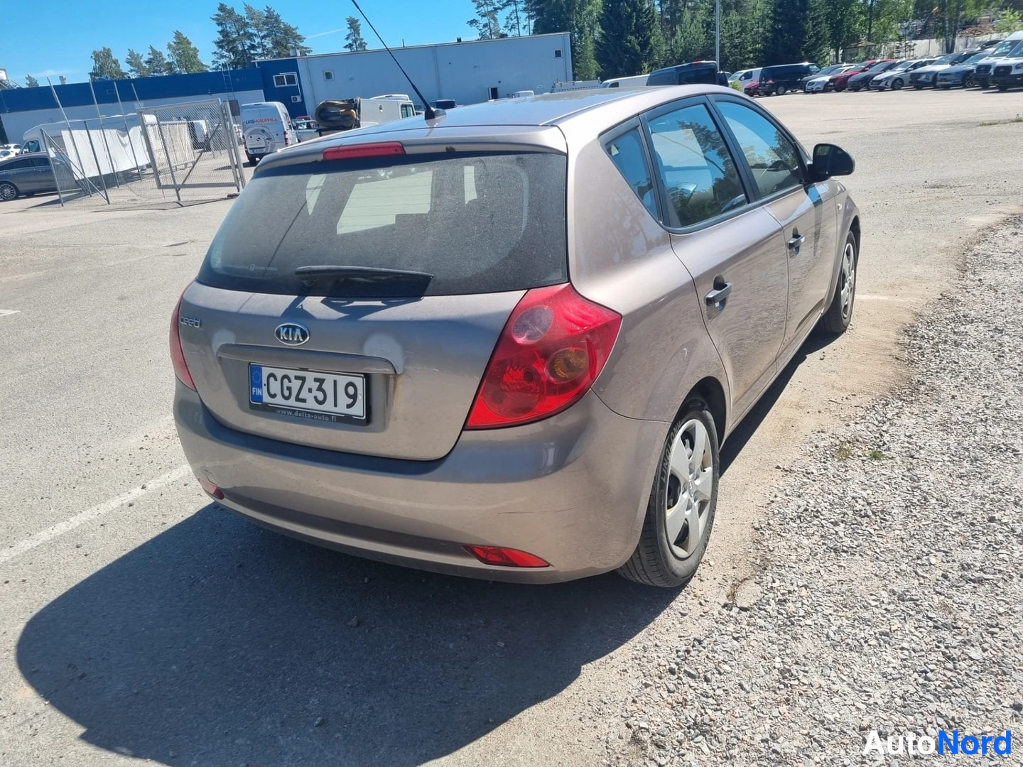 Takaviisto: Kia Ceed -henkilöauto takaviistostä oikealle kuvattuna parkkialueella; rekisterikilpi.