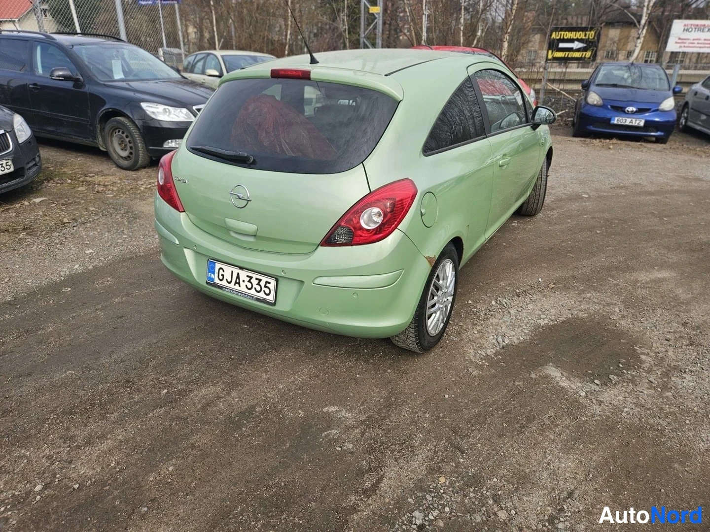 Takaviisto: Vaaleanvihreä Opel Corsa takakolmannelta kulmalta, takaosa ja oikea kylki näkyvissä, rekisterikilpi.