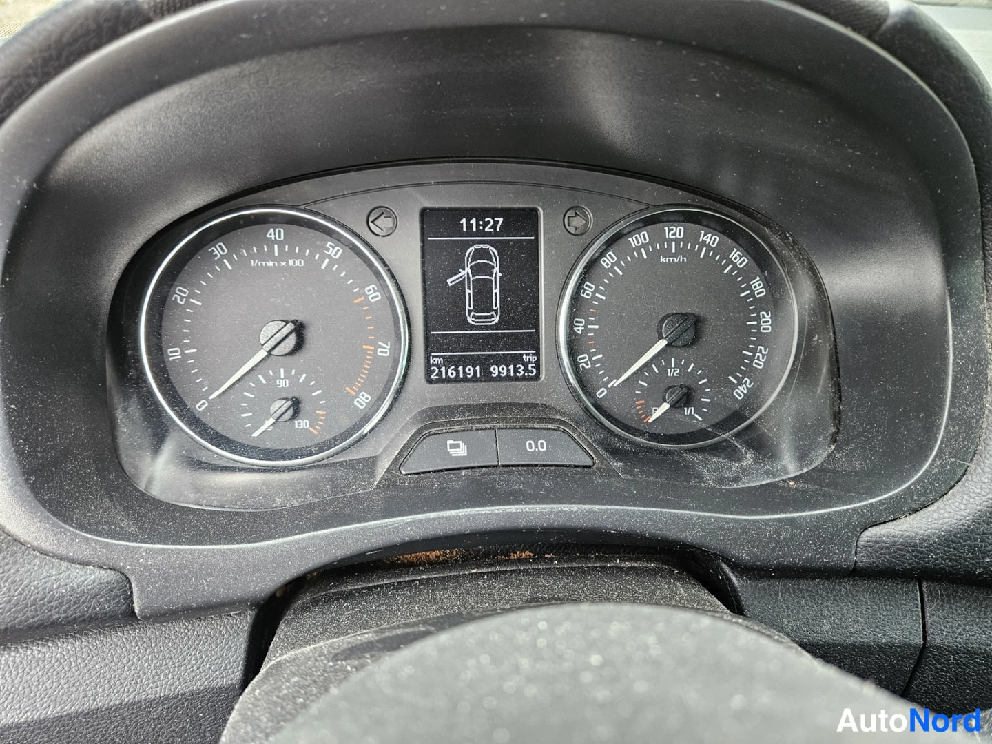 Yksityiskohta: Mittaristö lähikuvassa: nopeusmittari, kierroslukumittari ja näyttö, jossa lukee 11:27 ja kilometrilukema 216191 km.