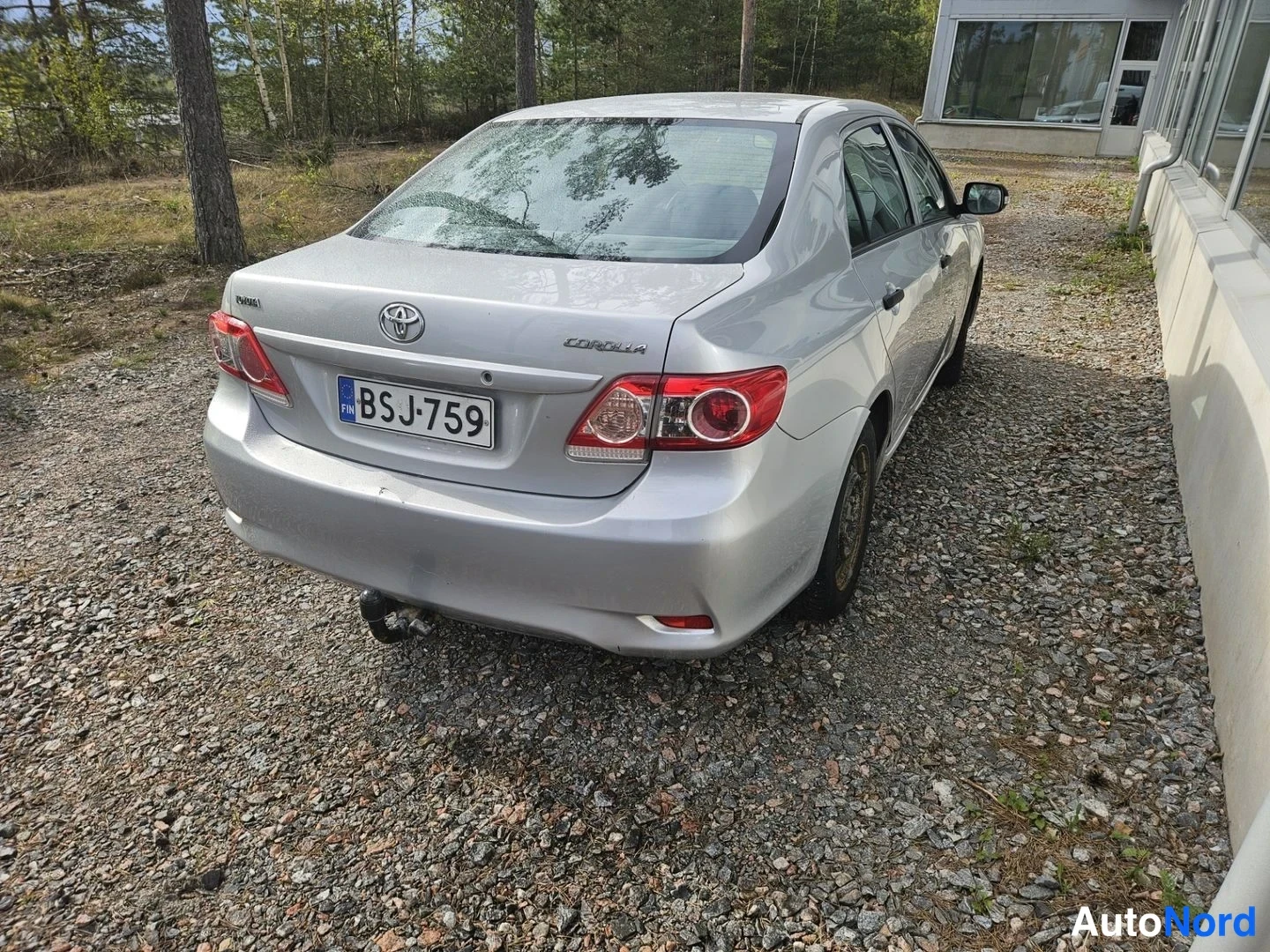 Takaviisto: Hopeanvärinen Toyota Corolla -henkilöauto kuvattu takaa oikealta, rekisteritunnus, takana vetoaisa.