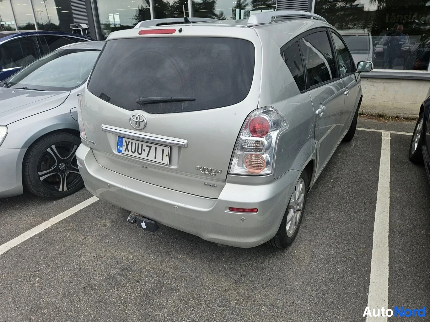 Takaviisto: Auton takapää takaa kuvattuna; takaluukku, Takavalot ja Toyota-merkki näkyvissä; parkkipaikalla muitten autojen joukossa.