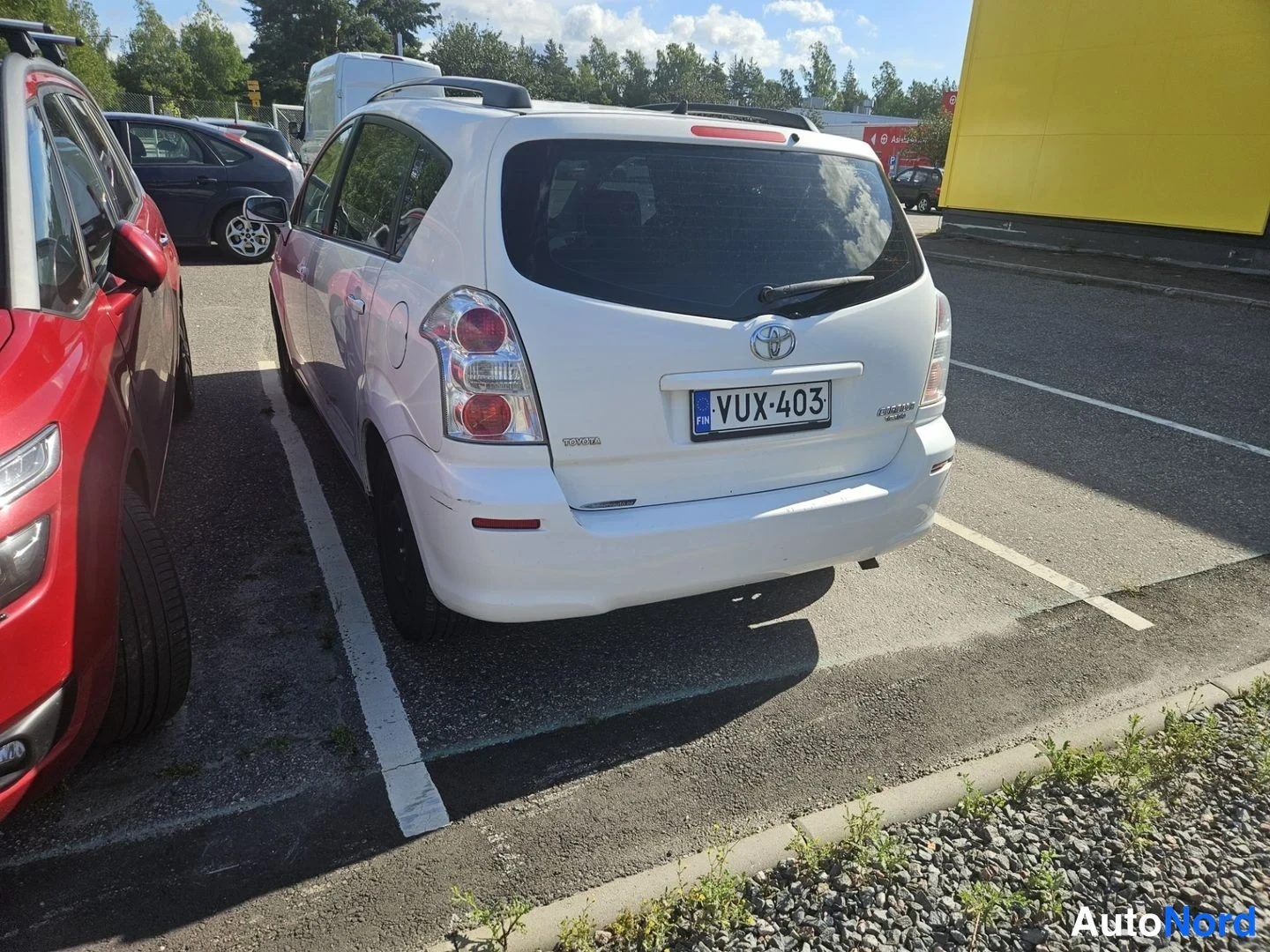 Takaviisto: Valkoinen Toyota Corolla Verso takakulmasta vasemmalta, rekisteritunnus, takavaihto ikkunanpyyhin näkyy.