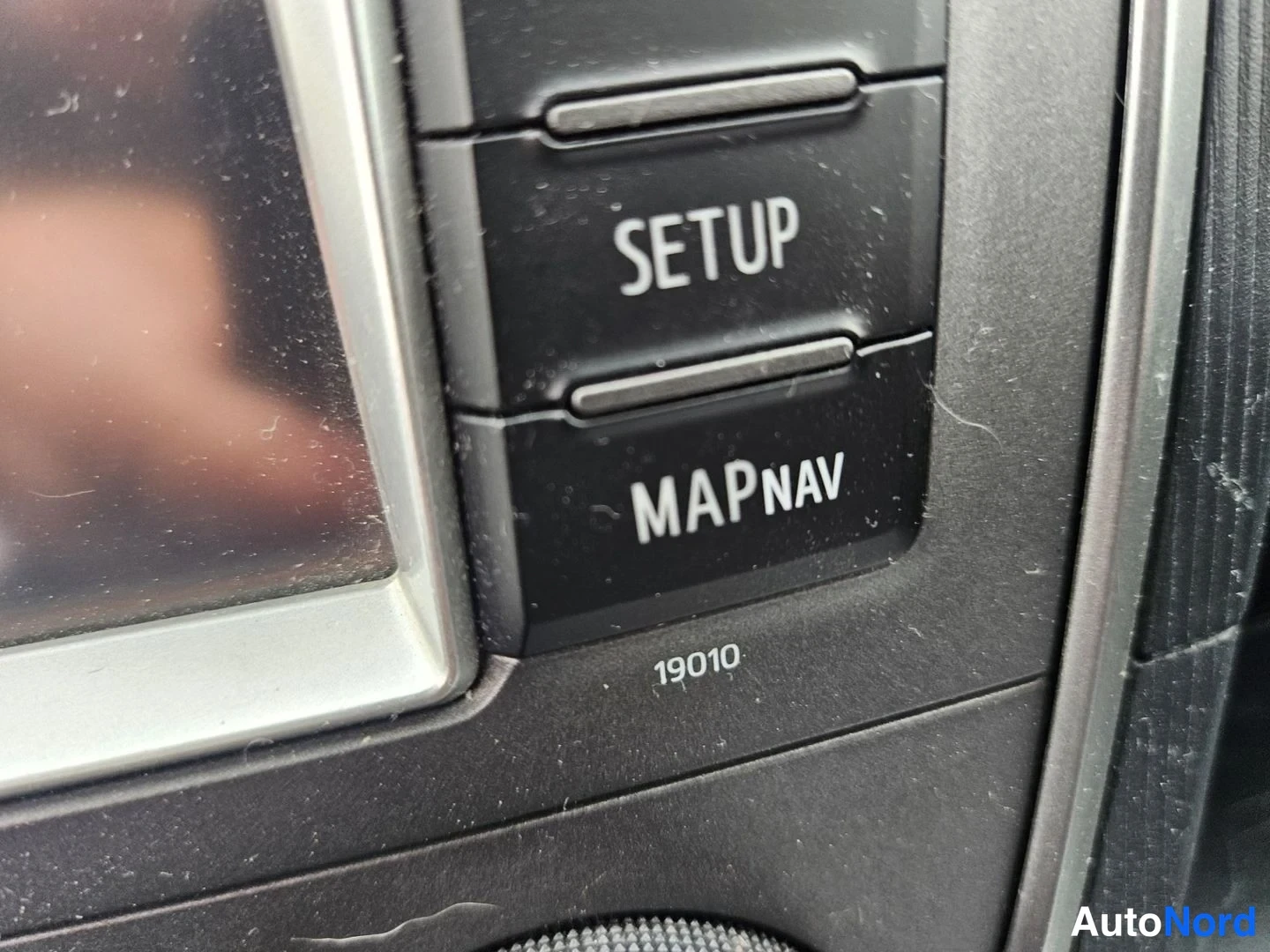 Muu: Asetuspainikkeet SETUP ja MAP NAV kuorma-auton kojelaudan keskikonsolissa.
