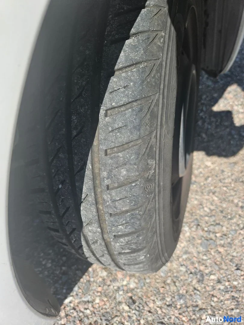 Yksityiskohta: Close-up of the vehicle's rear tire tread profile showing deep grooves and rubber texture next to the wheel well.
