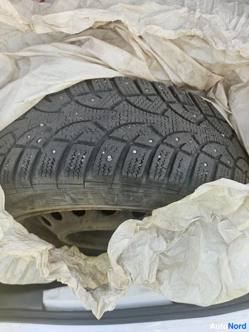 Yksityiskohta: Nokian-nastarenkaan lähikuva, rengas on paketissa sanomalehtipaperin seassa autossa.
