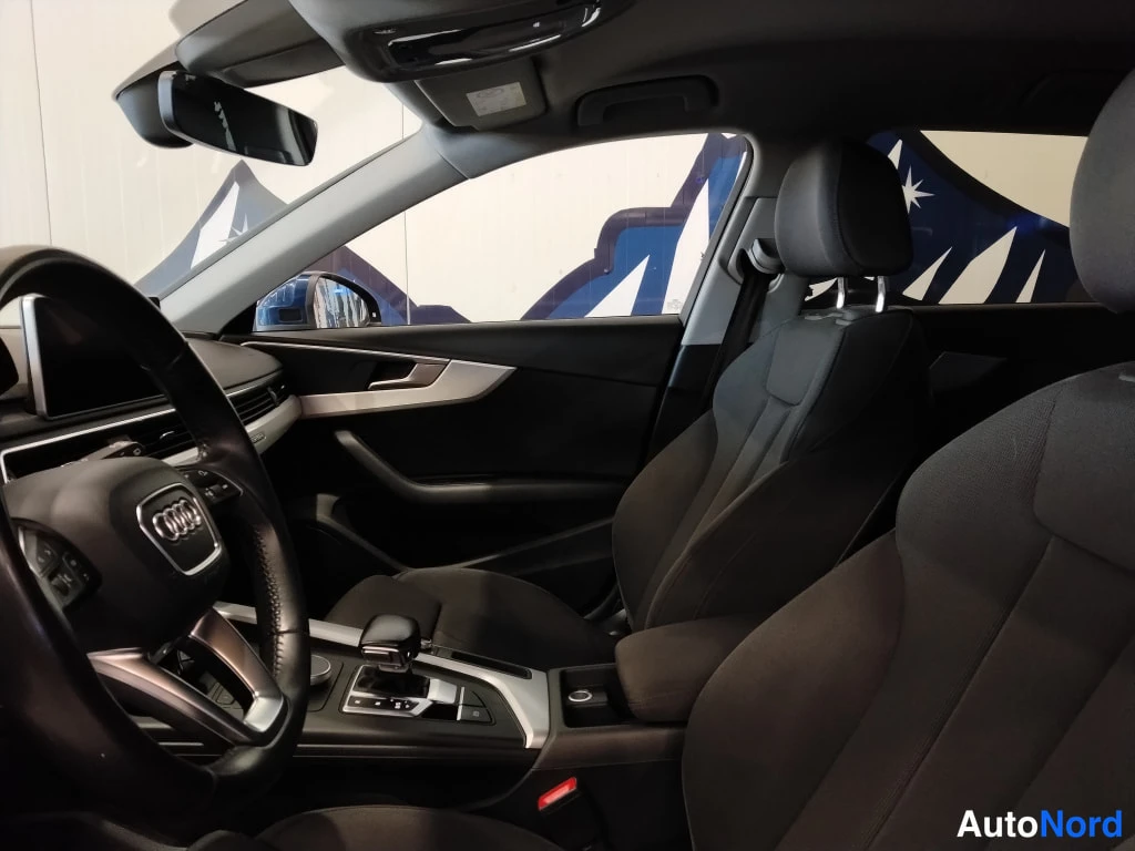 Sivulta: Audi A4:n etumatkustustila ja matkustajan ovi sisäpuolelta; mustat kankaat istuimet ja auton keskusyksikön logoovenkahvassa.