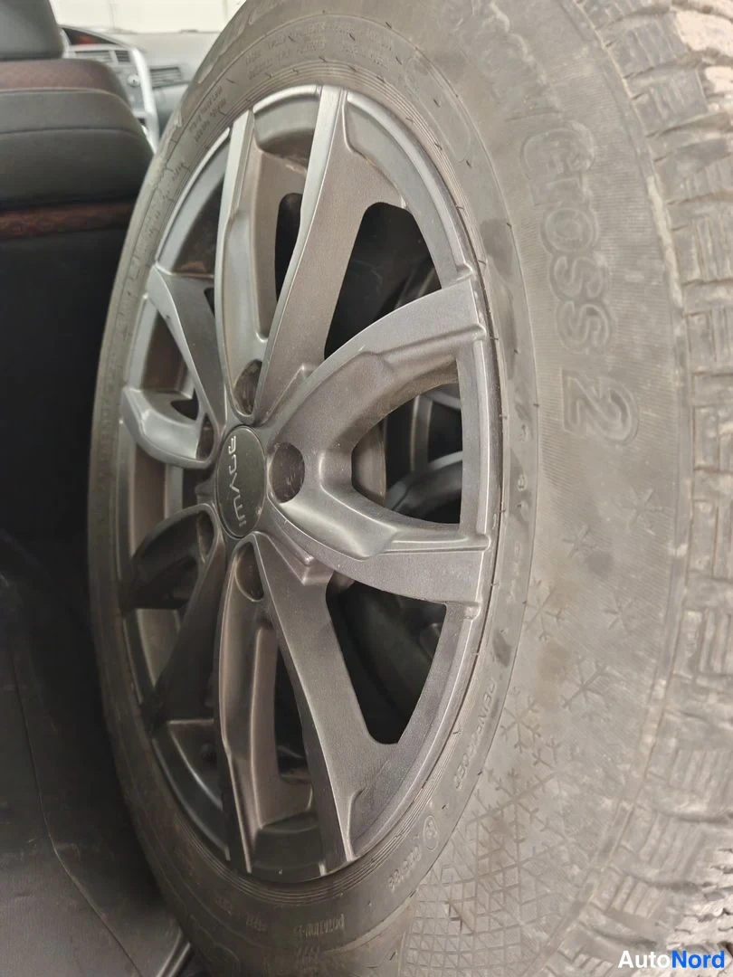 Muu: Kulutettu talvirengas, jonka sivussa lukee Cross 2, toyotan kevytmetallivanteessa autotilan sisällä.
