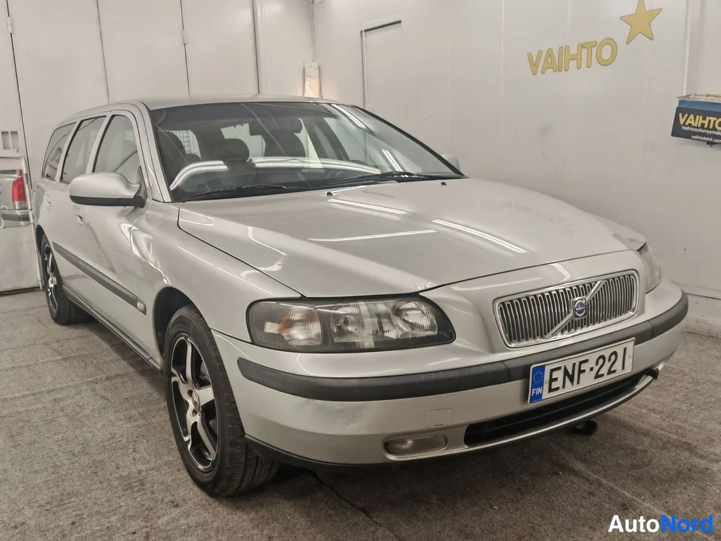 Etuviisto, nokka oikealle: Volvo V70 -farmari kolmesta neljäsosasta edessä oikealta, hopeanvärinen, rekisterikilpi.