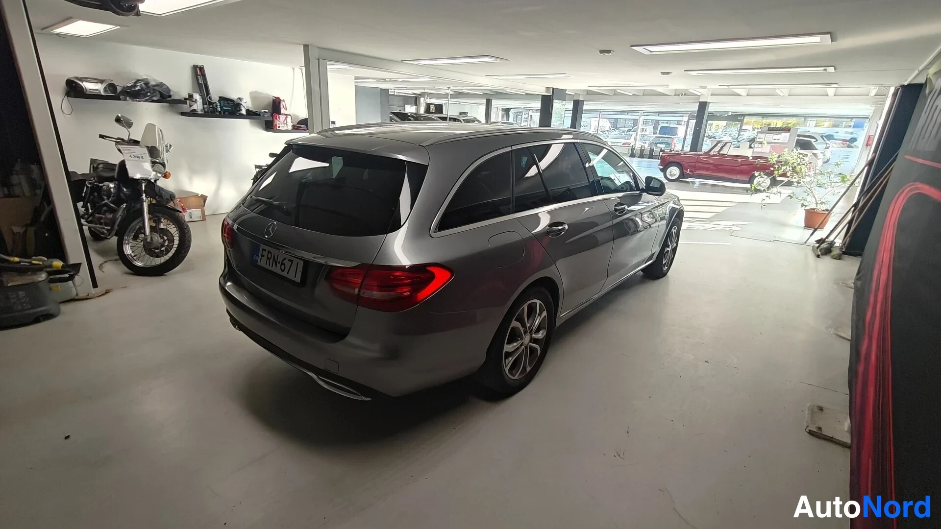 Takaviisto: Hopeanharmaa Mercedes-Benz C-asentoauto takaa vasemmalta kuvattuna autotallissa; rekisterikilpi.