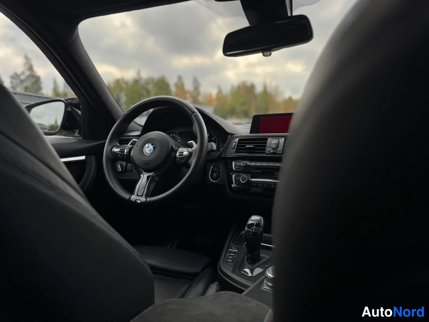 Muu: Ohjaamosta kuva: BMW-ohjauspyörä, kojelauta ja automaattivaihteen valitsin, tumma sisusta.