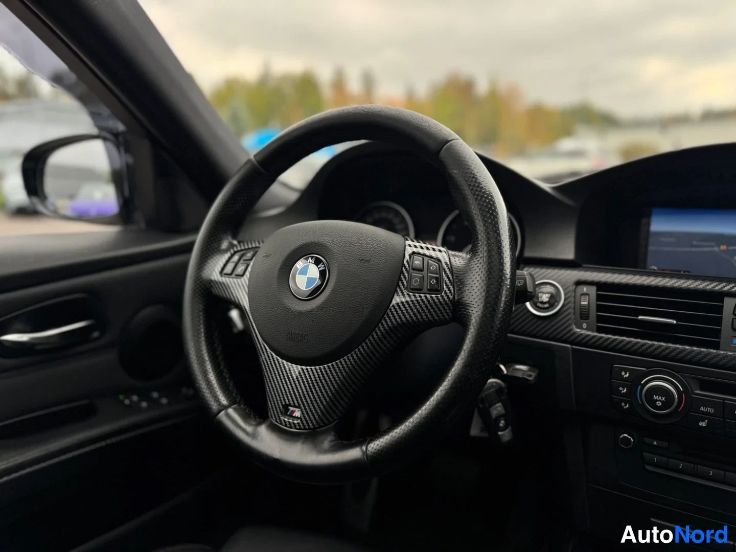 Muu: Lähikuva BMW M-monitoimiohjauspyörästä ja kojelaudasta, jossa näkyy Airbag-teksti ja automaattinen ilmastointi.