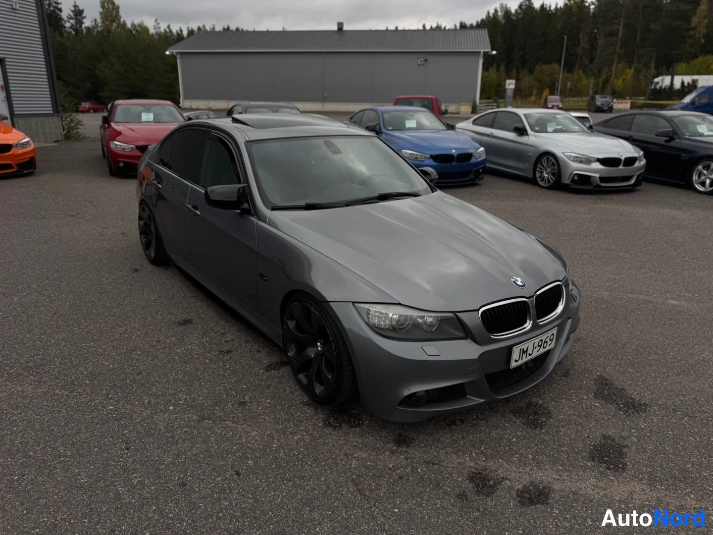 Etuviisto, nokka oikealle: BMW-sedan harmaana edestä vasemmalta kolmivartalokuvassa, nokka ja kylki näkyvissä, mustat renkaat.