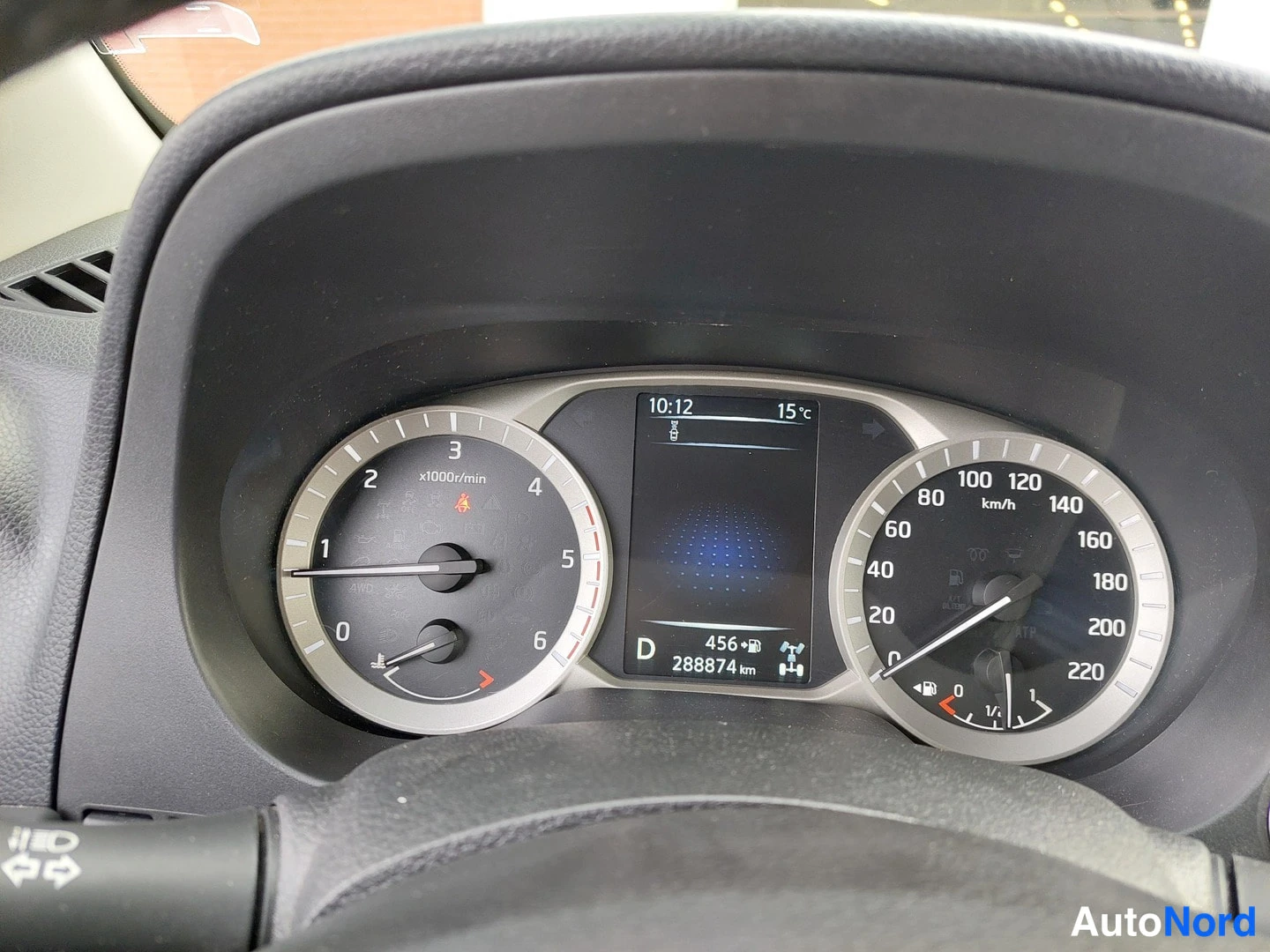 Yksityiskohta: Mittaristona takometri (0–6 x1000/min) ja nopeusmittari (0–220 km/h); näytössä kello 10:12, ulkolämpötila 15 °C, vaihde D ja yhteensä 288874 km.