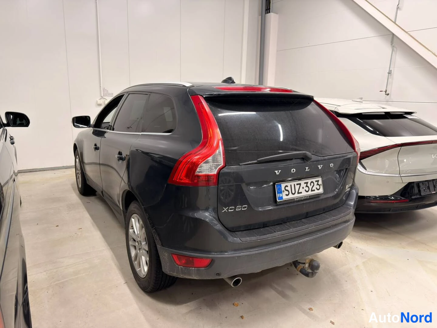 Takaviisto: Tummanharmaa Volvo XC60 takaa kolmesta neljänneksestä, takaluukussa VOLVO- ja XC60-tekstit, kilpi.