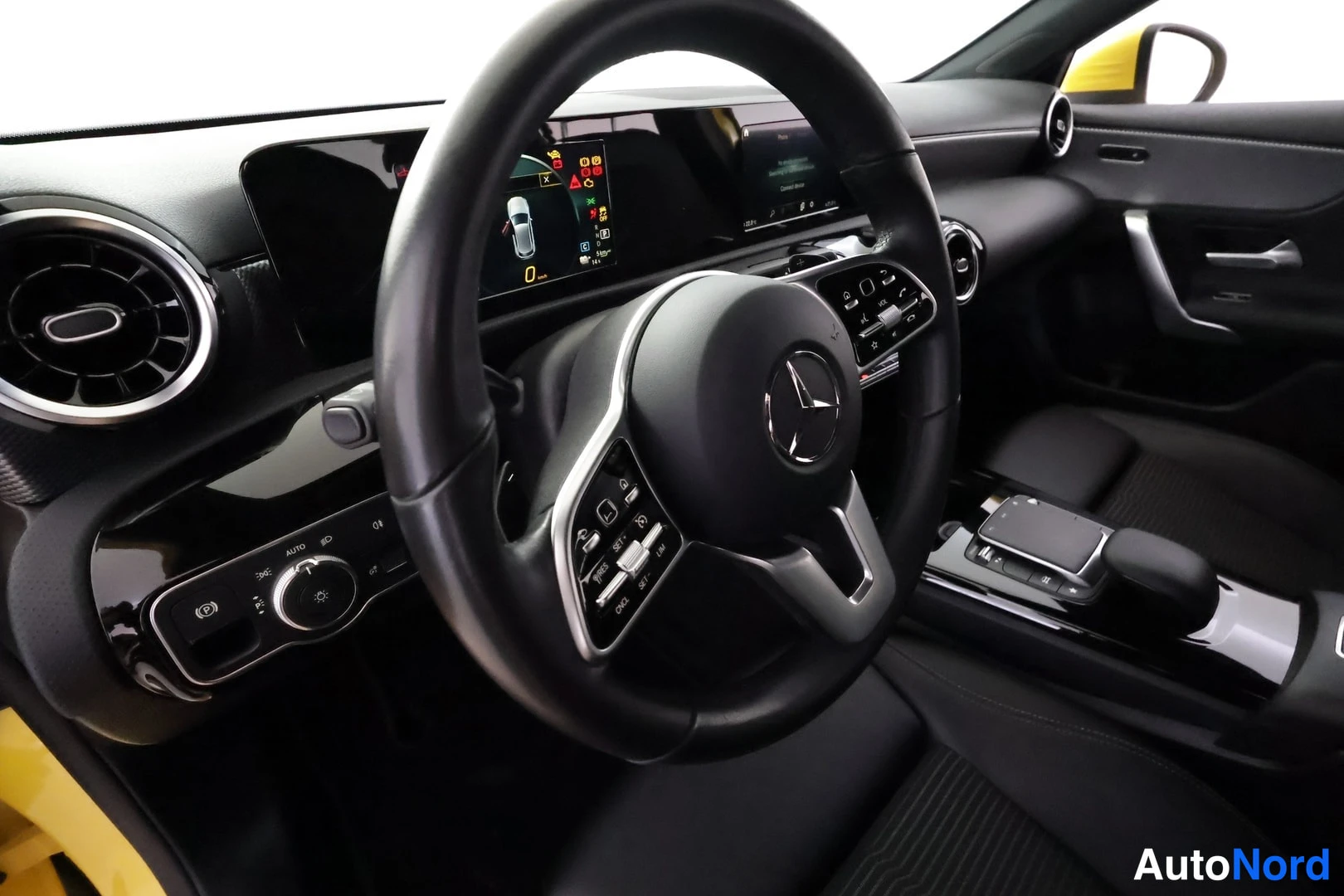 Muu: Ohjaamo vasemmalta: Mercedes-ohjauspyörä, digitaalinen mittaristo ja keskinäyttö, automaattivaihteen valitsin, tummat penkit ja keltainen runko ovessa näkyvissä