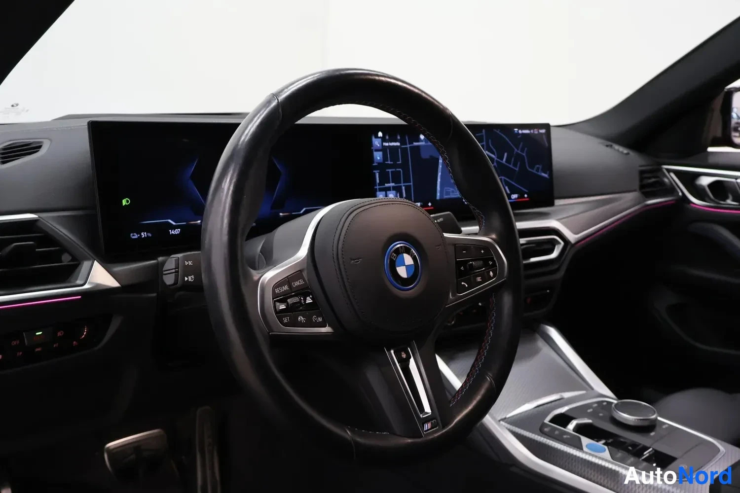 Muu: Auton ohjaamo: BMW-ohjauspyörä, laaja näytöistä koostuva mittaristo ja karttanäyttö.