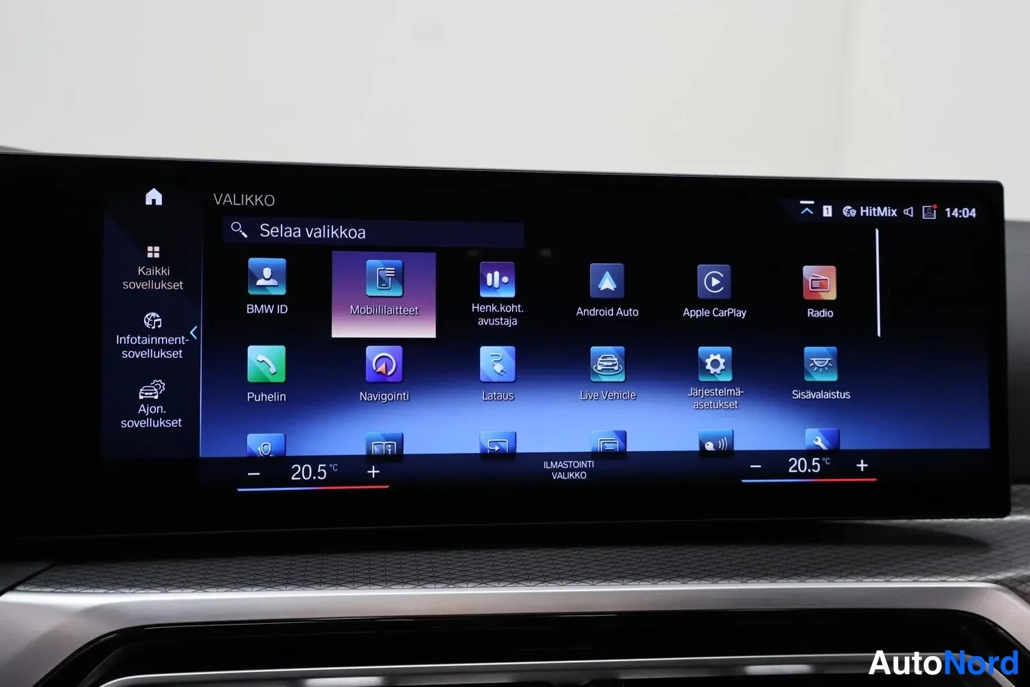Muu: Auton keskusnäytön valikko, jossa sovelluskuvakkeet kuten BMW ID, Mobililaitteet, Android Auto, Apple CarPlay, Radio, Puhelin, Navigointi, Lataus ja Ajon. sovel