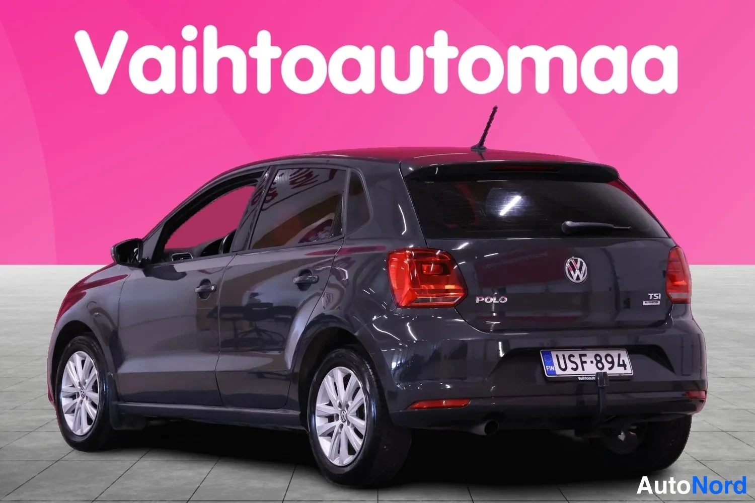 Takaviisto: Tummanharmaa Volkswagen Polo takaa vasemmalta kallistettuna, POLO- ja TSI-tunnukset takaluukussa, rekisteritunnus.