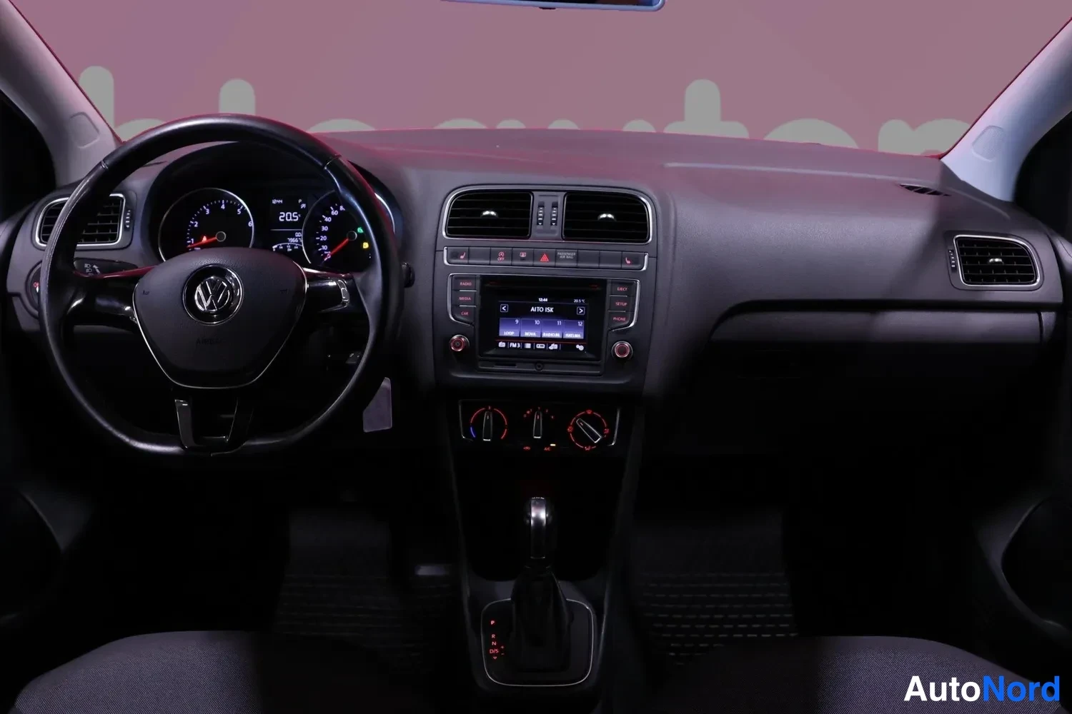 Yksityiskohta: Volkswagenin ohjaamo: ratin ja kojetaulun näkymä, keskellä radio ja ilmastointisäätimet, automaattivaihteen valitsin keskikonsolissa.