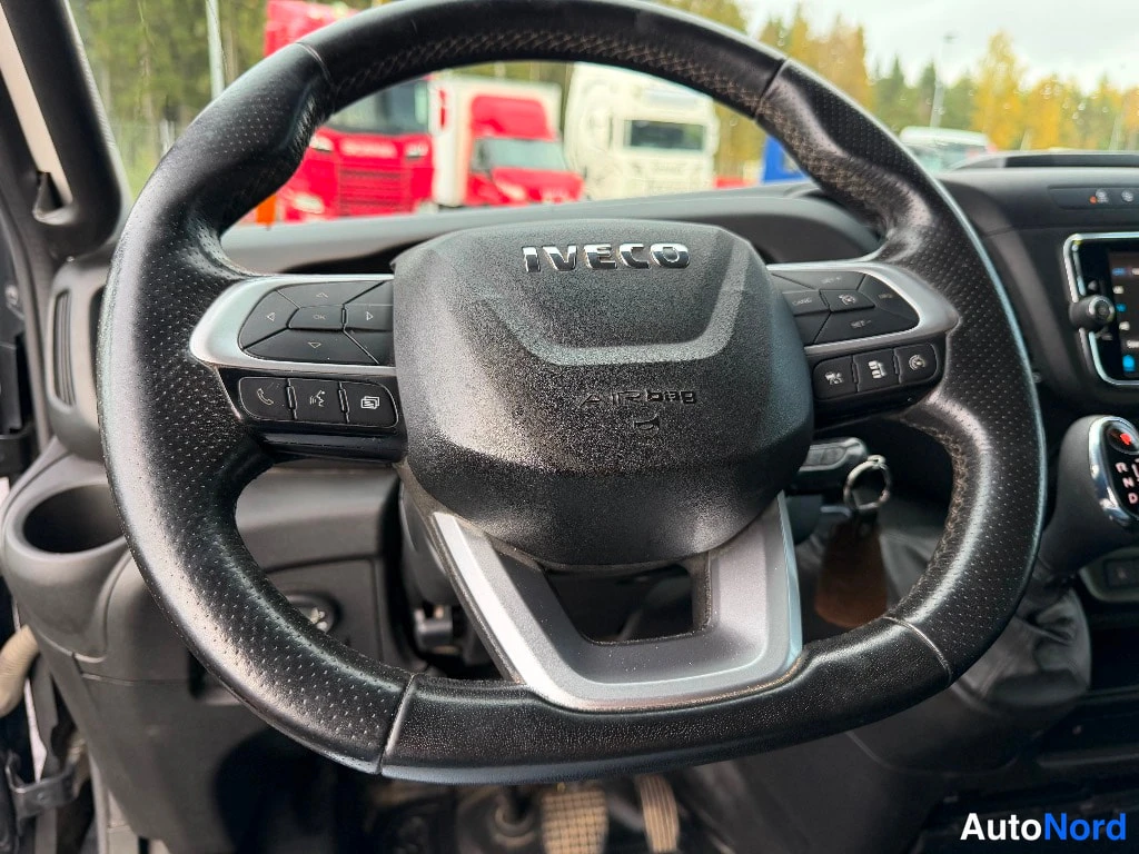 Muu: Ohjauspyörän lähikuva, keskossa IVECO-merkki ja AIRBEE-teksti, monitoimipainikkeet molemmin puolin, avain lukkorunkoon kiinnitettynä.