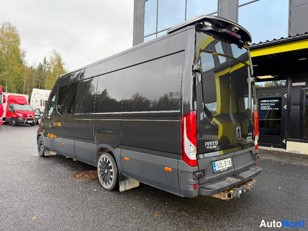 Takaviisto: Tummanharmaa Iveco Daily pakettiauto takaa viistosti vasemmalta kuvattuna; IVECO-teksti takaluukussa, rekisterikilpi ja harmaat alustaosat.