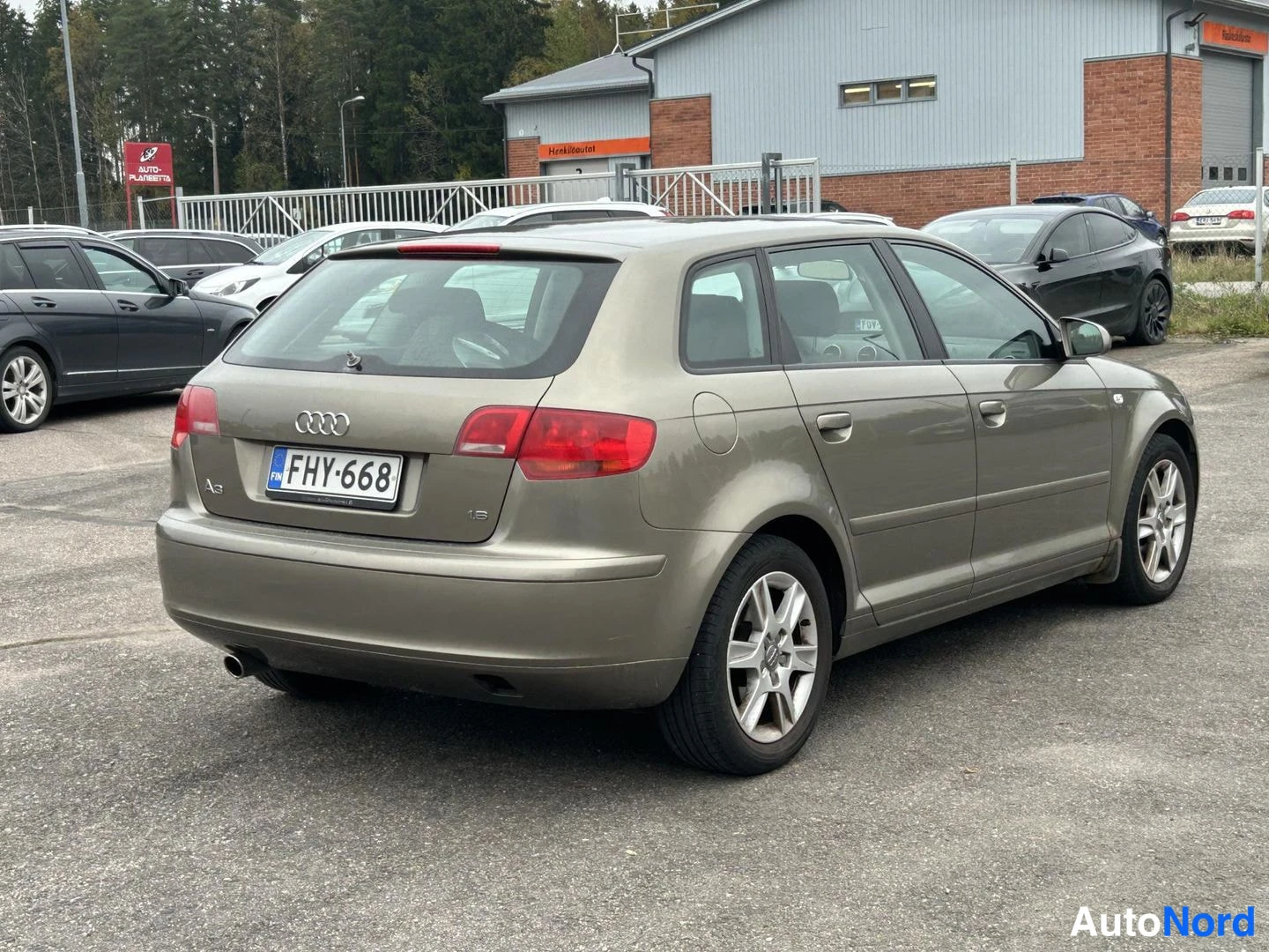Takaviisto: Beige Audi A3 Sportback takakolmannelta oikealta näkyvä kuva, takavalojen ja rekisterikilven kanssa.