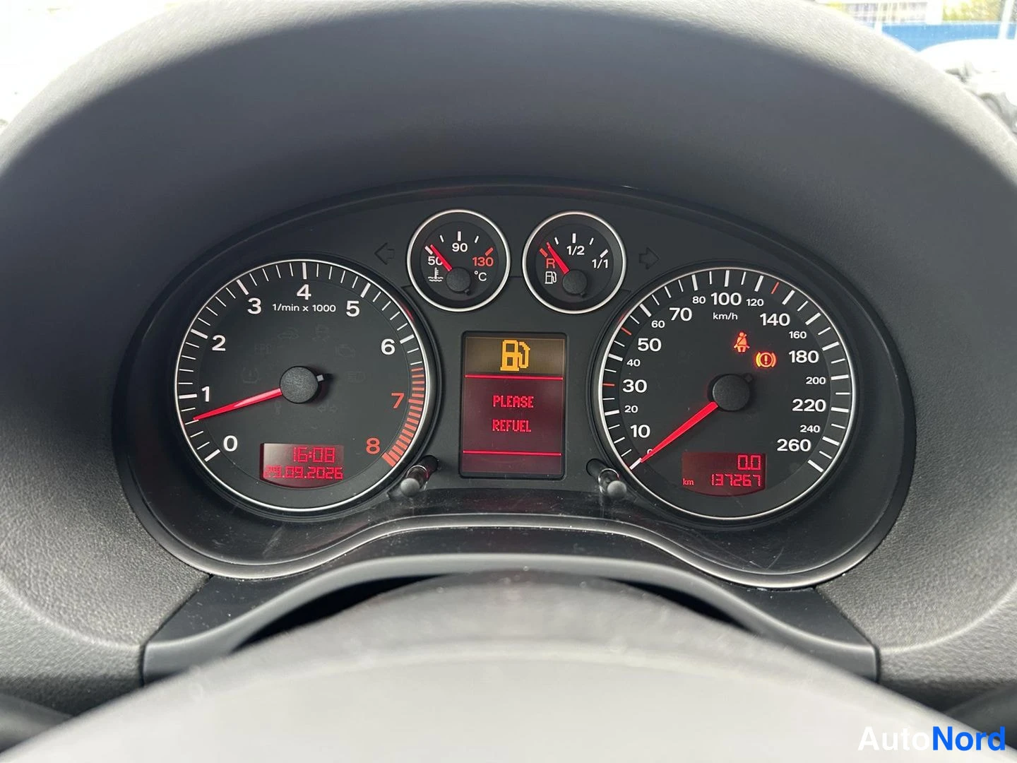 Muu: Ryömijäkojeiston lähikuva: kaksi analogista kierrosmittaria ja nopeusmittaria, keskiruudussa teksti PLEASE REFUEL, kokonaislukema 131267 km, kellonaika 16:08 ja