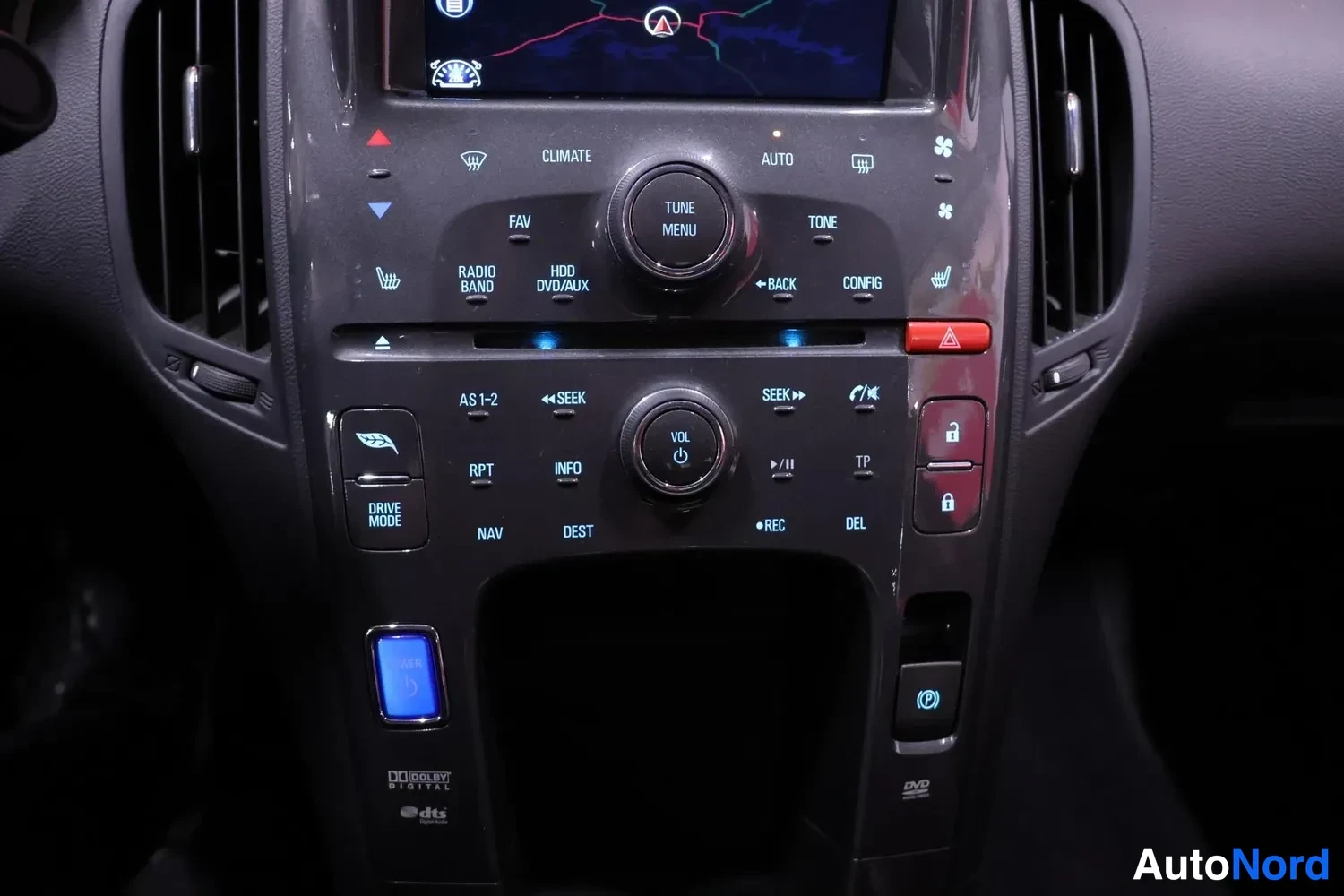 Muu: Keskikonsoli ja infotainment-napit lähikuvassa: nappien tekstit kuten CLIMATE, AUTO, TONE, HDD/DVD/AUX, DRIVE MODE, Dolby Digital ja DTS -logot, DVD-merkintä.