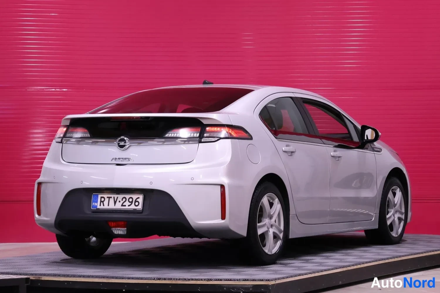 Takaviisto: Hopeanvärinen Opel Ampera takaviistosta, rekisteritunnus, punainen tausta.