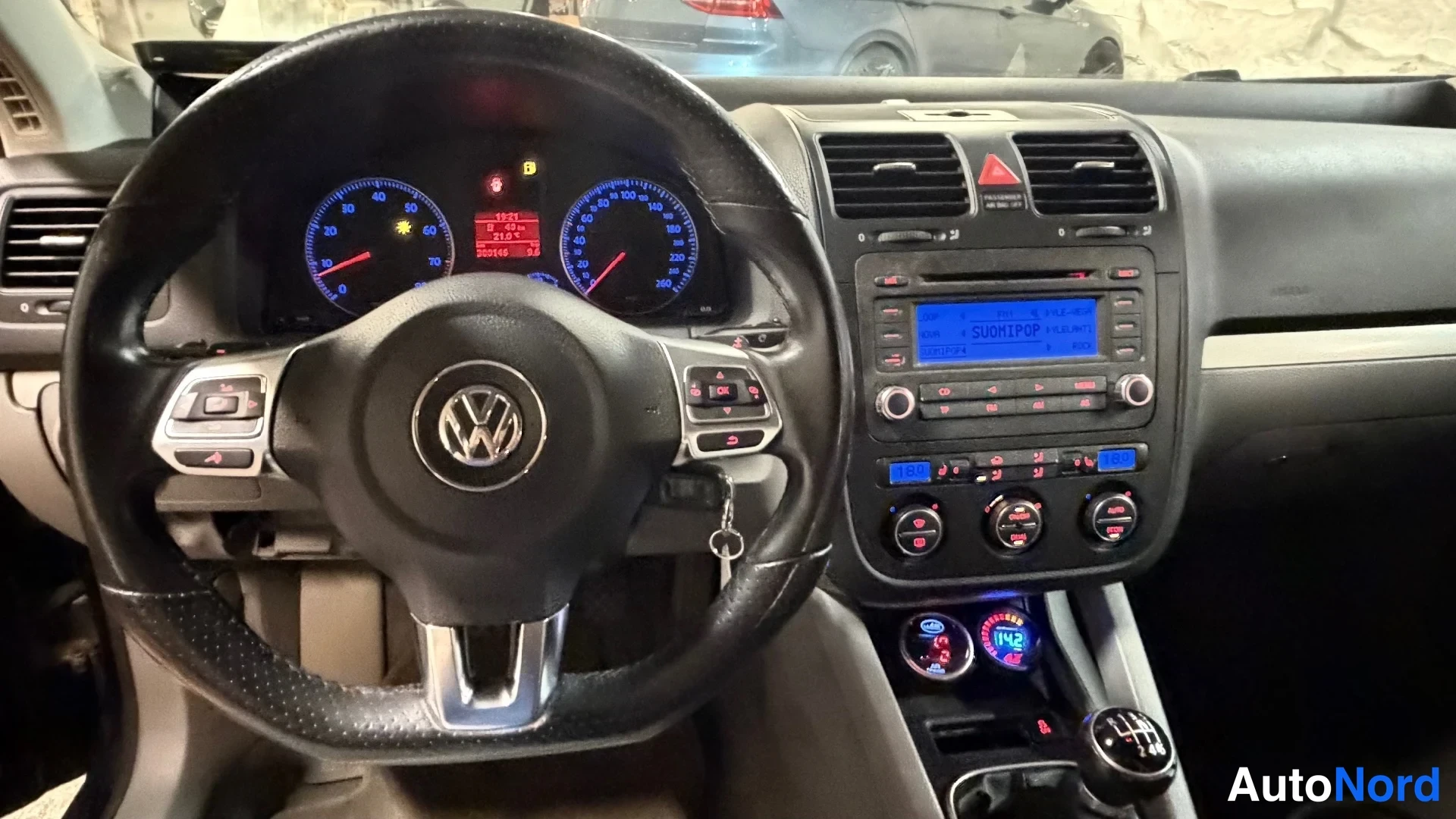 Muu: Volkswagen-ohjauspyörä ja kojelauta, sininen näyttö ruudulla teksti SUOMIPOP, vaihdelaatikko manuaali.