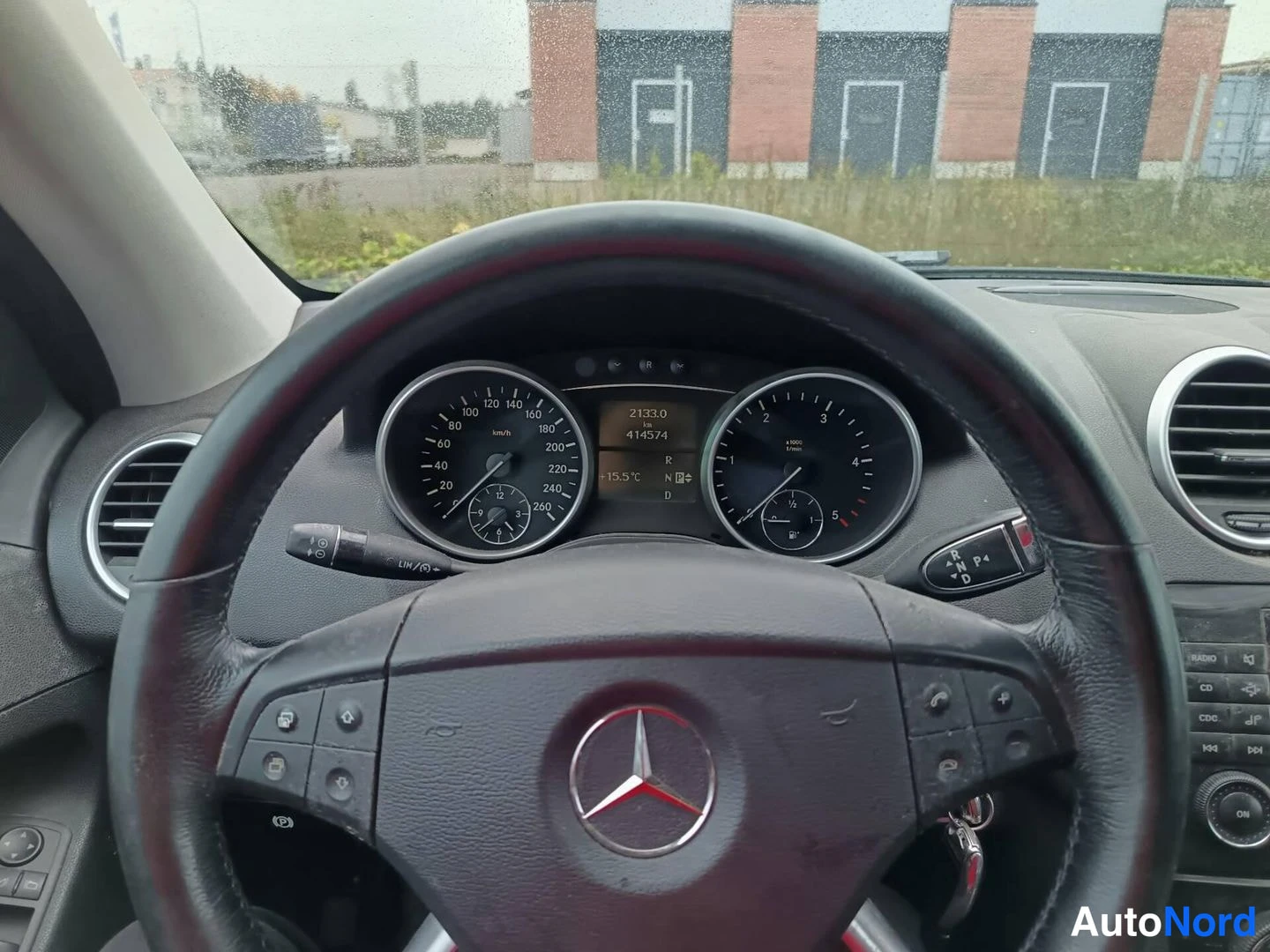 Yksityiskohta: Ohjaamon näkymä: Mercedes-merkillä varustettu ohjauspyörä ja mittaristo, näytössä lukemat 21330 km ja 414574