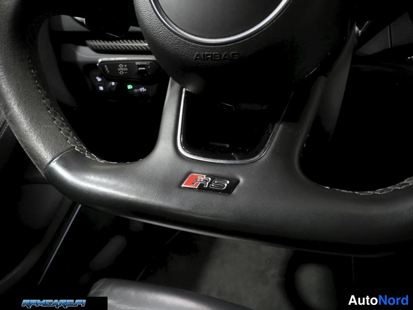 Muu: Sisäkuva: Audi-ratin taa osa ohjaustangosta, ratissa RS-merkki ja AIRBAG-teksti, väri musta.