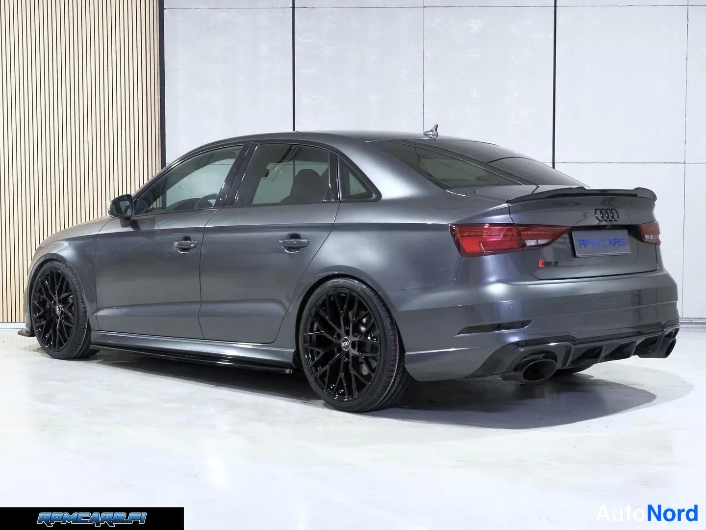 Takaviisto: Harmaa Audi RS3 Sedan takakulmasta, kaksoispakoputket ja musta spoileri, RPM Cars -teksti rekisterikilven paikalla.