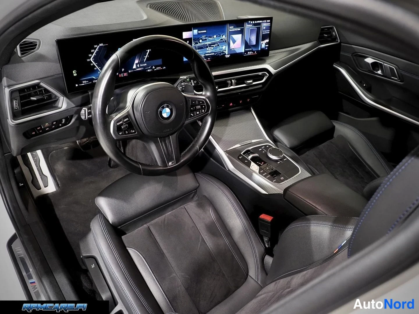 Sivulta: Auton etuistuinten ja kojelaudan näkymä: BMW-ohjauspyörä, laaja näyttö, keskikonsoli ja vaihteenvalitsin.