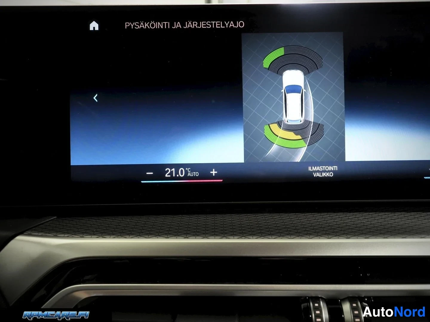 Muu: Infotainment-näytöllä 'PYSÄKÖINTI JA JÄRJESTELYAJO' -näkymä, jossa auton ympärille piirrettyjä anturivölähteitä, ja ilmastoinnin lämpötila 21,0 astetta.