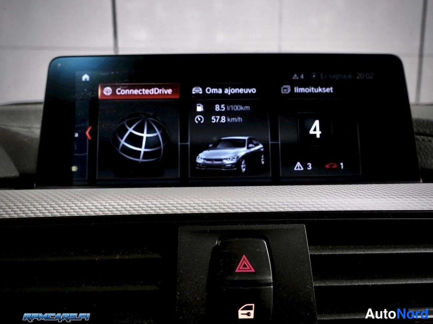 Muu: Auton tietoviihdenäyttö, jossa ConnectedDrive-valikko, teksti 'Oma ajoneuvo', kulutustieto '8.5 l/100km' ja keskinopeus '57.8 km/h'. Alareunassa kolmiovaroitusv