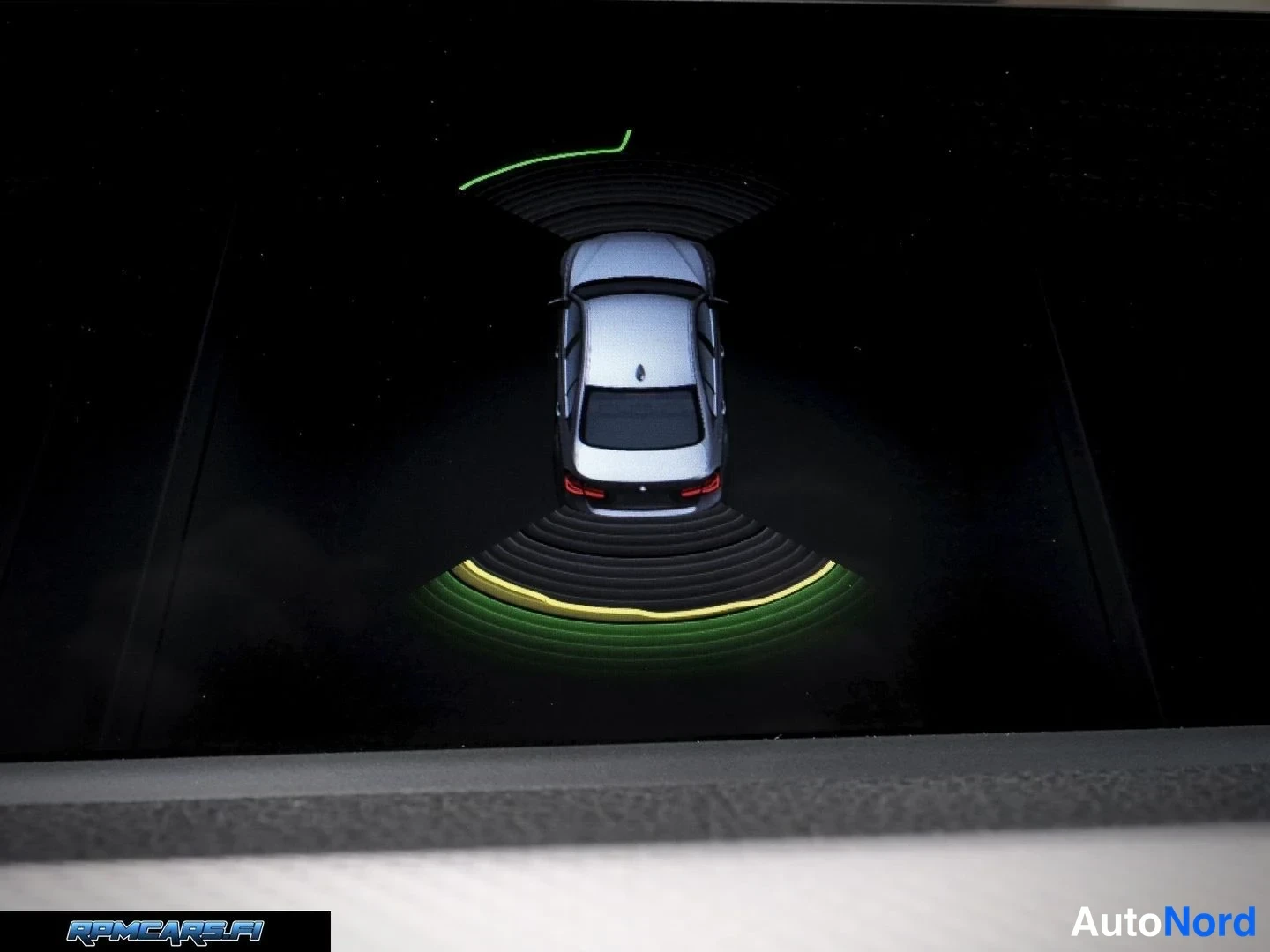 Muu: Infotainment-näyttö näyttää pysäköintitutkan grafiikkaa: auton mallikuva ylhäältä, vihreä ja keltainen kaari edessä ja takana.