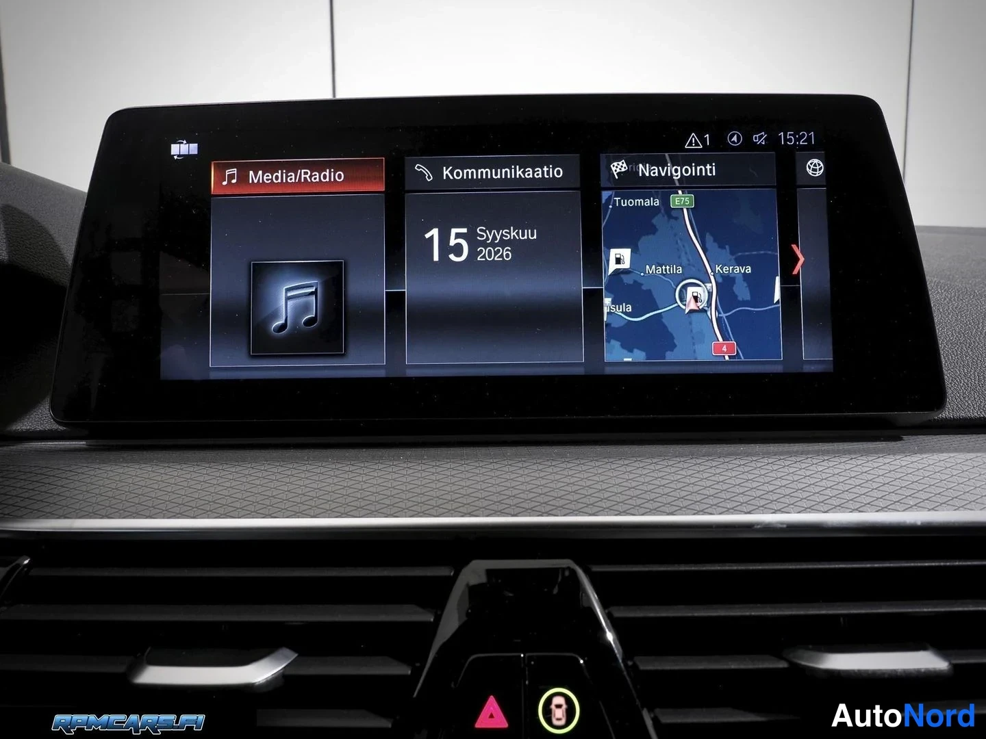 Sivulta: BMW:n infotainment-näyttö näyttää Media/Radio-, Kommunicaatio- ja Navigointi-valikot, joiden keskellä lukee 15 Syyskuu 2026.