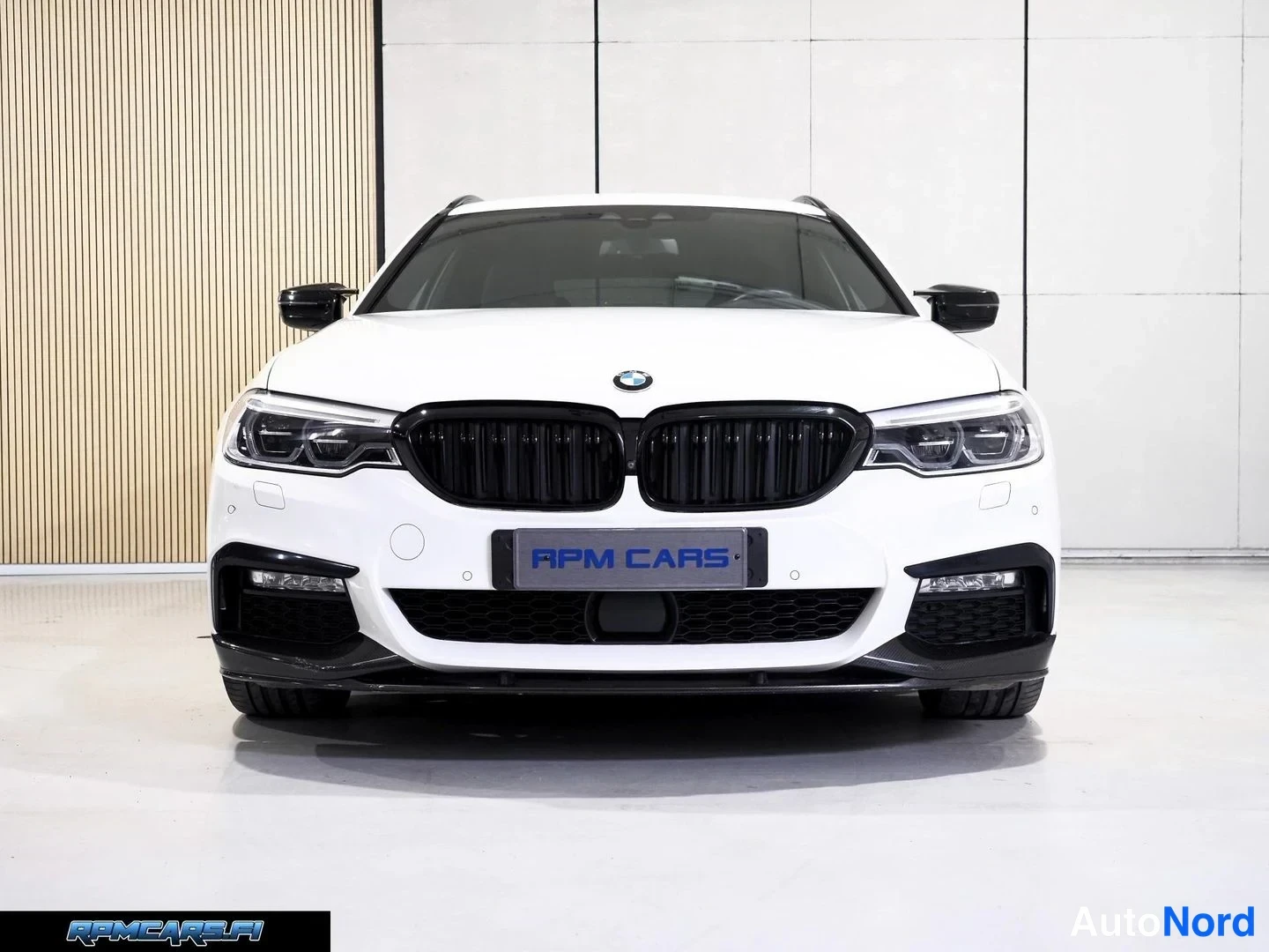 Edestä: BMW-sedanin etunäkymä edestä: valkoinen koripaneeli, musta etusäleikkö ja LED-etusovellukset studio-tyyppisessä tilassa.