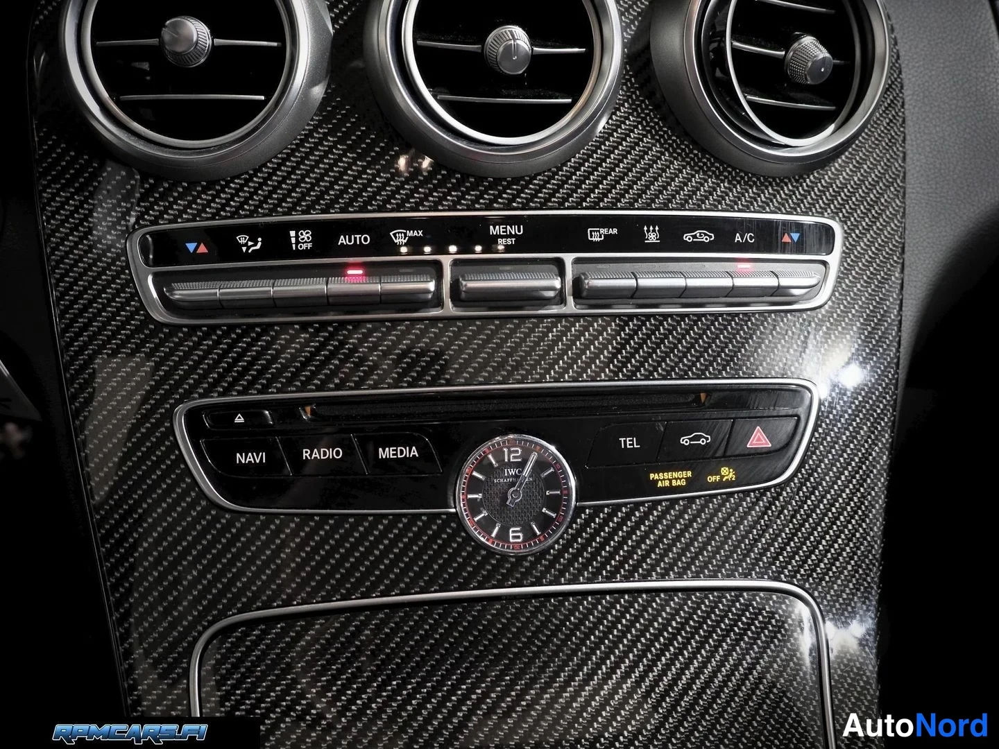 Muu: Lähikuva ilmastointipaneelista (AUTO, MAX, REST, A/C) ja multimediaohjaimista (NAVI, RADIO, MEDIA, TEL) sekä IWC Schaffhausen -analogikellolla, hiilikuitukuvioi